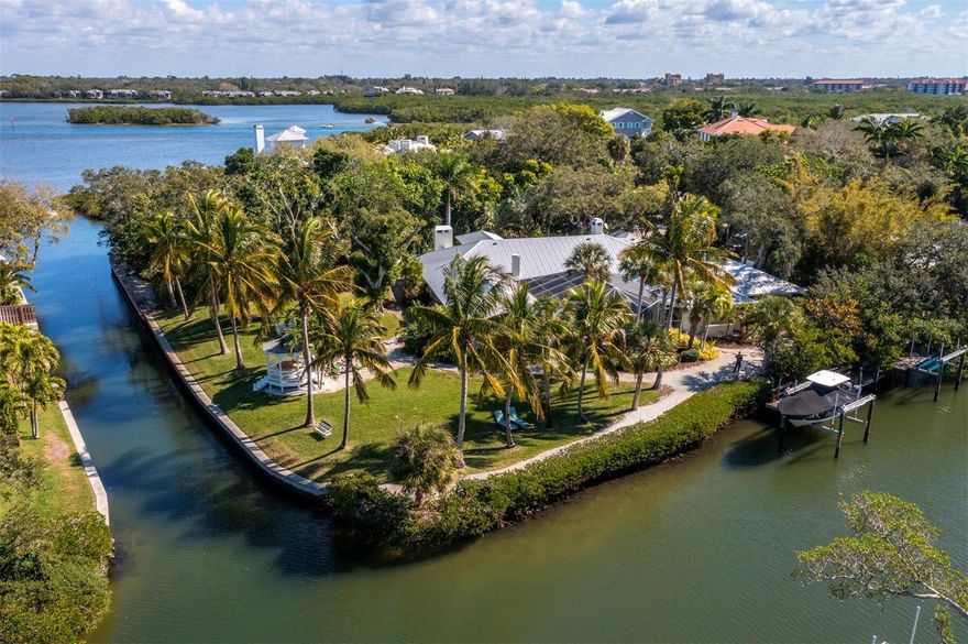 A boater’s dream! Nestled on the edge of Hidden Harbor with easy access to Roberts Bay, this rare listing is definitely noteworthy – a hidden treasure behind lush landscaping. Imagine passing through a tree canopied road to your own personal oasis. This breathtaking setting offers 317’ of water frontage, with NO bridges to the bay, on a private street near the renowned Siesta Key Beach. With 4,457 square feet, on a 31,000 sq ft lot, this 4 bedroom plus office, 5 bath home offers plenty of space to entertain family and friends. A gracious entry leads into the double front doors and seamlessly flows into the foyer and great room with sliding doors that open to the ideal outdoor living space and large backyard with canal views and partial bay view. This inviting open and airy floorplan offers many flex space options. The screened pool and spa area feels like a tropical retreat amidst the magnificent natural backdrop. A private dock with two boat lifts offers direct access for boating, fishing, or simply embracing the tranquility of waterfront living. The chef-friendly kitchen includes granite countertops, L-shaped island, wood cabinetry, and uppers with glass doors to display collectibles. The large and open great room features a second fireplace. Just off the great room, enjoy the walk-in wine cellar and a library/office with a fireplace that can easily be turned into a separate guest suite. The layout places three bedrooms and two baths on one side of the home - private and comfortable for family or visitors. Pool and backyard views enhance the expansive master bedroom suite – a true retreat. Highlights of the en-suite master bath include His and Her bathrooms with an adjacent walk-in closet. Other noteworthy features include crown molding, hurricane-rated windows, a maintained seawall, two boat lifts, outdoor kitchen, and an oversized two-car garage. The spacious side-entry garage offers ample room for vehicles and storage, while the generously sized paved driveway ensures no shortage of parking spaces. Wander to one of the gulf coast barrier islands, explore the shopping of downtown Sarasota, or enthuse in the many recreational opportunities that the area offers. This exceptional home offers a seamless blend of indoor living and a captivating outdoor ambience, creating the perfect space for relaxation and entertainment - live a dream and make it home.