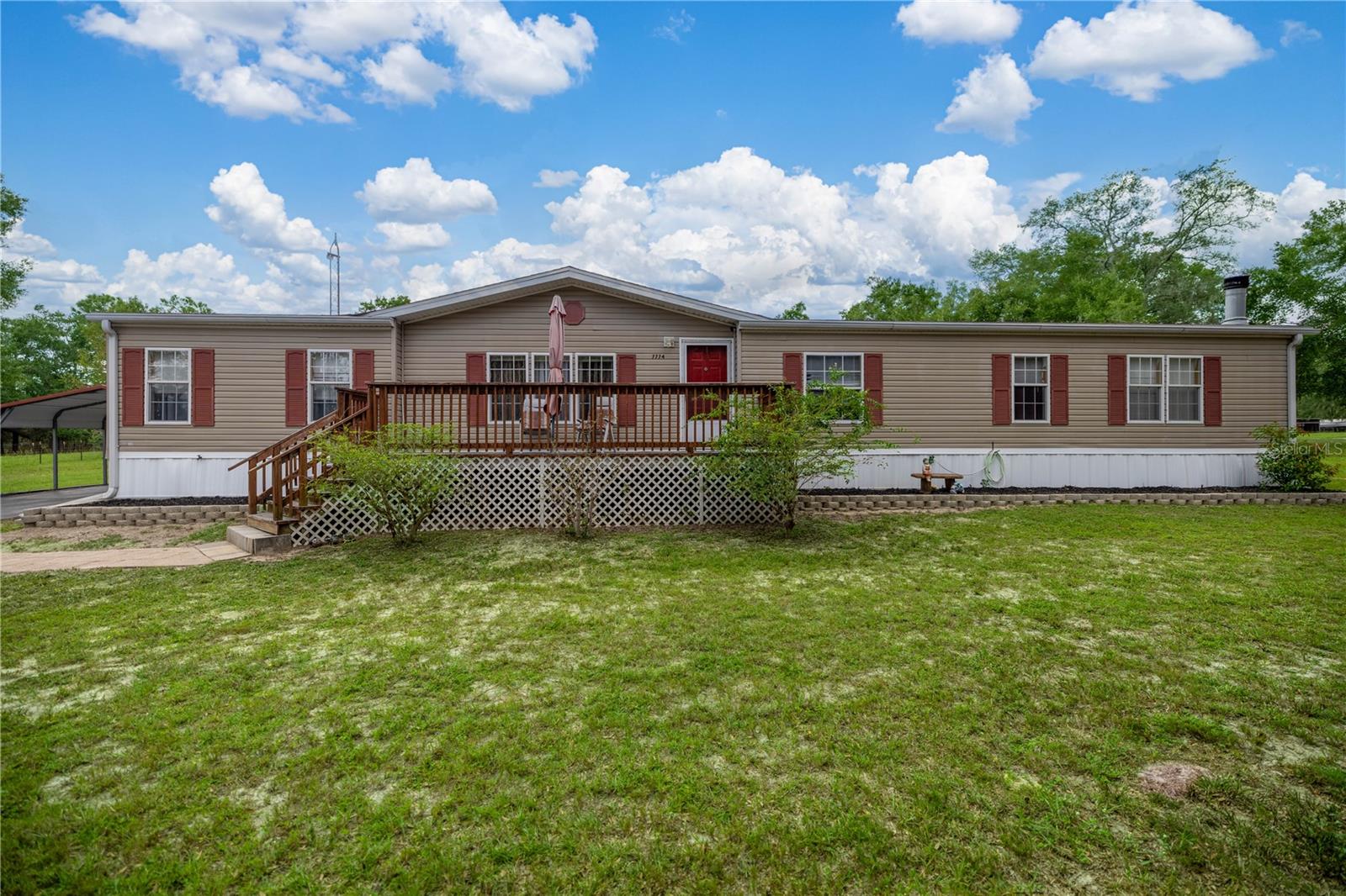 Spacious 4-bedroom, 2-bath home on 1.59 acres in Dunnellon, FL! This well-maintained property offers multiple living spaces, custom finishes, and plenty of room for family or guests. The oversized kitchen provides abundant cabinetry and storage. The dining area features a beautiful built-in hutch and sliding glass doors leading to the back patio. The living room is large and open, while the family room boasts a wood-burning fireplace and a wet bar with sink and cabinets. The primary suite includes custom cabinetry crafted by The Cabinet Monkey. Three additional bedrooms with generous space. A wide hallway with built-in cabinets and desk adds convenience. Outside, enjoy front and back wooden decks for entertaining. A 14 x 24 workshop with electricity, workbench, and shelving, plus three carports, provide plenty of storage. The 1.59-acre fenced property also includes handmade hurricane shutters crafted by the owner. This home offers country living with space to spread out while still being by Dunnellon’s amenities — for multi-generational living or anyone seeking room to grow!