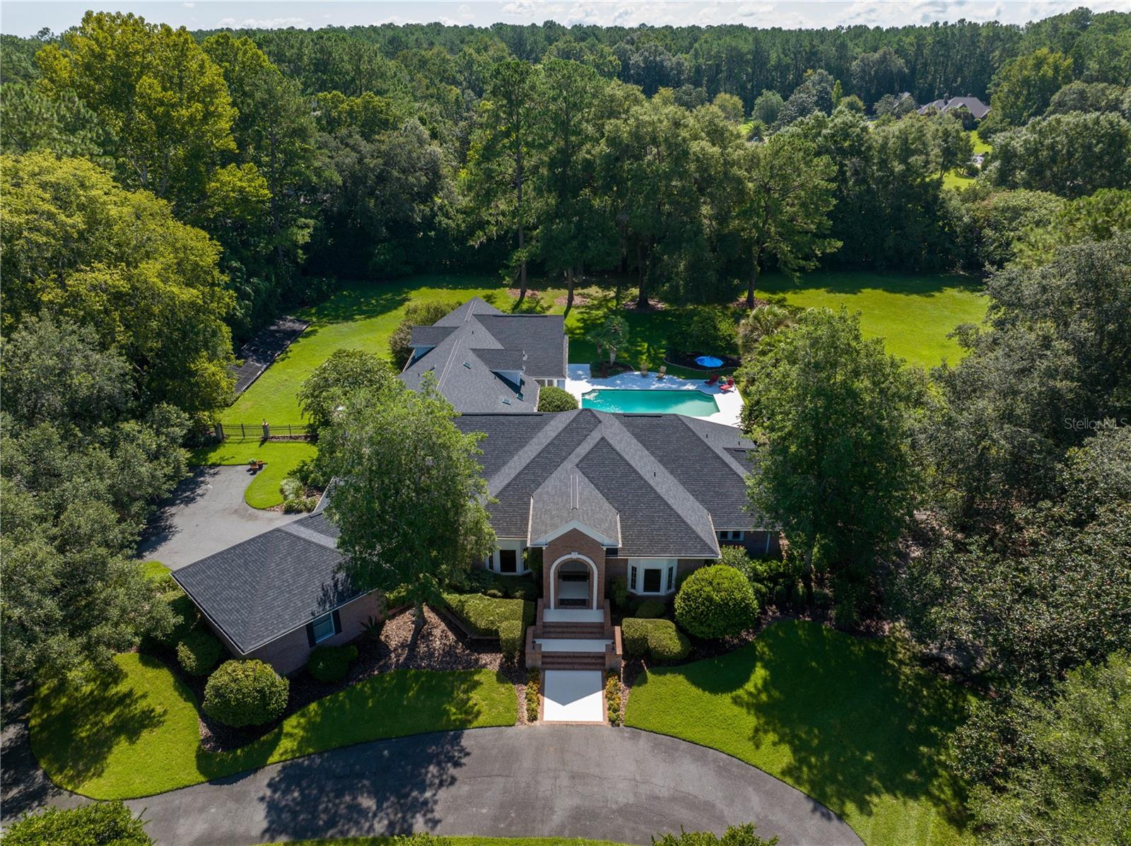 Quality is evident in every inch of this stunning updated Brick Home in the Gated Community of Sawbuck. Originally built in 1987, renovations have been in full swing since 2021. The Gourmet Kitchen was relocated and designed by Carson’s Cabinetry. Appliances include Wolfe Gas Range Top, Convection Oven plus a Steam Convection Oven great for baking, Vent a Hood Exhaust System, Subzero Double Refrigerator faced with Wood and Mirrored panels, Glass China Cabinets, Miele Dishwasher and a Panda Marble Countertop. You have to see it and cook in it to believe the quality and its functionality for the chef of the family. Adjacent to this Fabulous Kitchen, you’ll find a gathering room with a walnut cabinet to hold your China and Glassware, Wet Sink and Two Refrigerators which is ideal for your intimate celebrations. Enjoy your walk in Butler's Pantry with a Miele Coffee Maker, 4 door Samsung Refrigerator, Bosch Dishwasher, Prep Sink and loads of functional cabinets for storage. Don’t miss the full-sized Wine Refrigerator. French Oak Flooring by Villa Borghese was recently installed throughout the home (with the exception of the Media/Game Room) and is exquisite. The Family/Media room has a wet bar complete with an Ice Machine and Subzero Double Refrigerator Drawers plus Built-in Book Cases and access through French Doors to the Covered Open Porch and huge Salt Water Pool beyond. It’s the perfect space for private time, movie night or entertaining your friends and neighbors. The Owner's Suite is spacious and the Bathroom features two new spacious custom closets with wood cabinetry, huge walk-in shower plus free-standing modern tub, soft close drawers, double sinks with Man-Made Quartz countertops and loads of storage space. Enjoy the Luce Feather Mineral Spring Pearl Wall while relaxing in your Soaking Tub. There is a large room across from the Owner's Suite that has served as an office but can be used as a nursery or a 6th bedroom with a closet and access to the remodeled full guest bath. The Screened Porch is now a permanent Sun Room with 2 Split Systems allowing comfortable year-round enjoyment. The covered lanai and open deck overlook the beautiful salt water pool with plenty of space for your chaise lounges. 7 security cameras patrol this property with inhouse recorder (no Monthly Charge). New Pool Sweep for easy pool maintenance. There is nothing as satisfying as having complete privacy on your own two acres of beautifully landscaped fenced property.