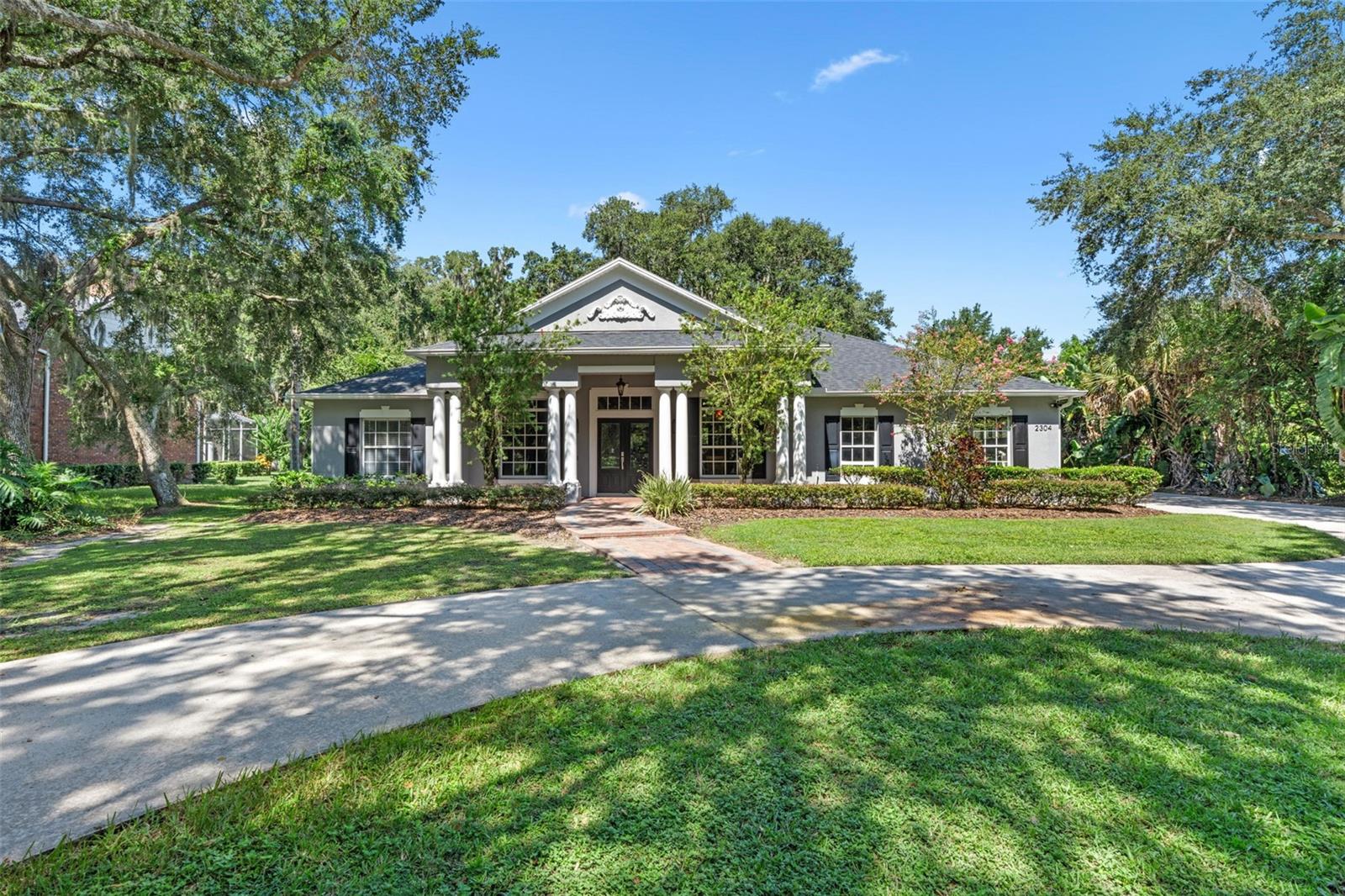 Welcome to 2304 Indian Mound Trail in Kissimmee — a graceful blend of timeless charm and tranquility, nestled within the private, gated community of Hidden Harbor. This stately Colonial-style residence, built in 2002, is set on a beautifully landscaped 1-acre lot with a circular driveway — perfect for welcoming guests with ease and sophistication.
Step through the grand columned entryway into a sunlit foyer featuring decorative flooring — a stylish and durable choice that sets the tone for the home’s elegant, thoughtful layout. To the right, a formal dining room invites gatherings and special occasions, while the adjacent formal living room offers flexible use as a sitting room or home office — both spaces designed with refined architectural detail.
At the heart of the home is the spacious, open-concept family room, where decorative concrete flooring continues, adding a touch of contemporary flair that beautifully complements the room’s natural light and openness. This space flows seamlessly into a chef’s kitchen that’s equally suited for everyday living or entertaining. Herringbone tile floors, granite countertops, stainless steel appliances, a generous center island, and an expansive pantry make this kitchen both functional and inspiring.
The luxurious primary suite offers a serene retreat, complete with a spa-style en-suite bath featuring a garden tub, separate shower, and dual vanities. From here, enjoy convenient access to a private home gym — a unique space that supports wellness right at home.
Upstairs, a versatile loft provides an additional area for relaxation, creativity, or media. On the opposite wing of the residence, four additional generously sized bedrooms and two full bathrooms provide a thoughtful layout with comfort and privacy in mind.
Outdoors, the expansive backyard is a true extension of the living space — ideal for enjoying the Florida sunshine, dining al fresco, or relaxing beneath mature trees. Residents of Hidden Harbor enjoy access to private community amenities, including tennis courts and a fishing dock on scenic Lake Tohopekaliga — all within minutes of Central Florida’s renowned attractions, recreation, and dining.
2304 Indian Mound Trail is more than a home — it’s a place where everyday living meets elevated design, where thoughtful spaces invite connection, and where comfort and elegance come together in perfect balance.
