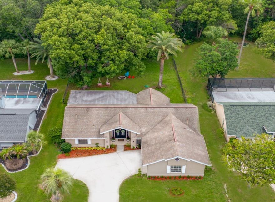 Tucked into the heart of Beacon Woods, this thoughtfully remodeled 3-bedroom, 2-bath home delivers the kind of indoor-outdoor Florida living most buyers only dream about. Welcome to this beautiful - move-in ready home, fully updated in (2023) and waiting for you.
This home features luxury vinyl plank floors throughout the main living areas and all three bedrooms, with tile in both bathrooms. Recent upgrades include a new water heater (2024), new water softener (2025), and new appliances (2023). The spacious main living area features soaring vaulted ceilings and triple sliding glass doors that open completely to a huge covered screened-in patio, seamlessly extending your living space into the gorgeous, shaded backyard, especially in Florida's cooler months. Mature trees and palms, fruit trees, and raised garden beds make this private fenced backyard a true outdoor retreat. The newly remodeled kitchen features quartz countertops, new appliances, a stylish backsplash, and an oversized single-basin sink. Just off the kitchen, a sun-drenched breakfast nook wrapped in bay windows overlooking park-like setting backyard — the perfect spot to start your morning. The open floor split bedroom layout ensures ultimate privacy. The primary suite features high ceilings, a completely remodeled en-suite bathroom, a massive walk-in closet, and sliding doors that open directly to the patio. The first oversized guest bedroom is revealed by pocket doors and offers high ceilings with flexibility for however you envision using the space. The third bedroom features coffered ceilings and gorgeous views of the backyard. The guest bathroom features a stunning stone sink vanity and a full bathtub. A spacious two-car garage offers room for a workbench and extra storage, a generous size attic provides additional storage. Residents enjoy access to a community center, large swimming pool, and tennis courts for just $33/month HOA. Hudson Beach is just 10 minutes away for those breathtaking Gulf sunsets views, close to downtown New Port Richey. With low HOA fees, modern updates throughout, and the Gulf Coast just minutes away, this is the perfect Florida lifestyle home you've been waiting for- move-in ready and priced to sell.