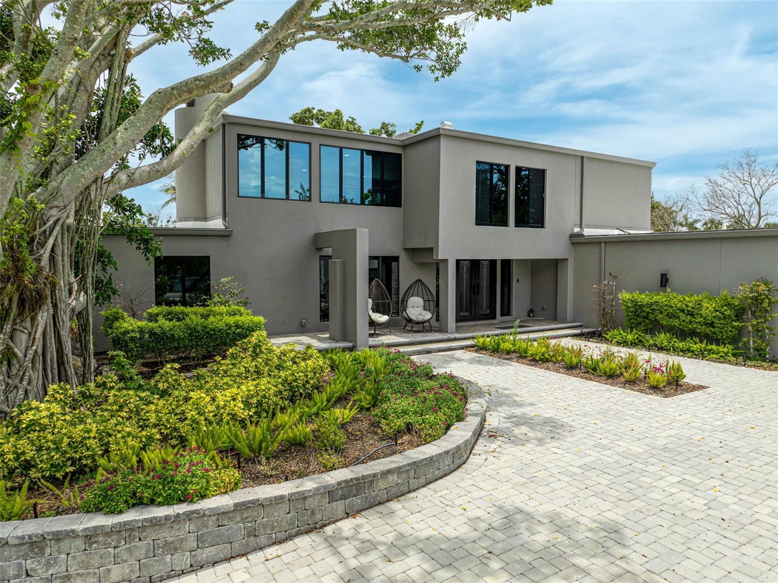 Designer Waterfront Living on Treasure Boat Way – Rare Value Meets Lasting Style
Modern Waterfront Estate on Siesta Key | 512 Treasure Boat Way
Perfectly situated on a spacious .44-acre corner lot in one of Siesta Key’s most sought-after boating communities, this fully renovated modern estate offers over 5,000 square feet of sophisticated living. With 3 bedrooms, 4.5 bathrooms, and a dedicated media room, the layout is both functional and refined.
Enjoy deep-water dockage on a wide canal with no fixed bridges and direct access to Sarasota Bay—ideal for boaters looking to explore the Gulf of Mexico with ease. The home’s high flood elevation and no history of flooding provide peace of mind and lower insurance premiums, adding even more value to this exceptional property.
Inside, dramatic design meets everyday comfort. Step through the doors to find soaring ceilings, a custom open-tread staircase with walnut treads, and a striking stone feature wall. Walls of glass flood the interiors with natural light, highlighting European porcelain flooring, designer lighting, and a double-sided fireplace that anchors the open living spaces.
The gourmet kitchen is a showstopper—designed for both entertaining and daily living—outfitted with quartz countertops, flat-panel cabinetry, floating shelves, and a full suite of premium appliances. The luxurious primary suite includes private pool access and a spa-inspired bathroom with a freestanding soaking tub, dual vanities, and bespoke tilework.
The dedicated media room features sliding glass doors that open to a private courtyard, offering a quiet, flexible space ideal for movie nights or casual relaxation.
Treasure Boat Way has been thoughtfully renovated to preserve its original mid-century style while modernizing with sleek industrial touches. The result is a home that is sophisticated, private, and relaxing.
Outside, tropical landscaping and an expansive backyard set the tone for true waterfront living. Multiple lounge areas and seamless indoor-outdoor flow make this a perfect setting for entertaining or unwinding, with captivating water views from nearly every room.
Whether you’re searching for a primary residence, a vacation retreat, or an income-generating investment, 512 Treasure Boat Way checks every box—offering modern updates, premium waterfront access, and a short stroll to Siesta Key Village and Siesta Beach.
Schedule your private showing today to experience the pinnacle of luxury waterfront living. **No flood damage**