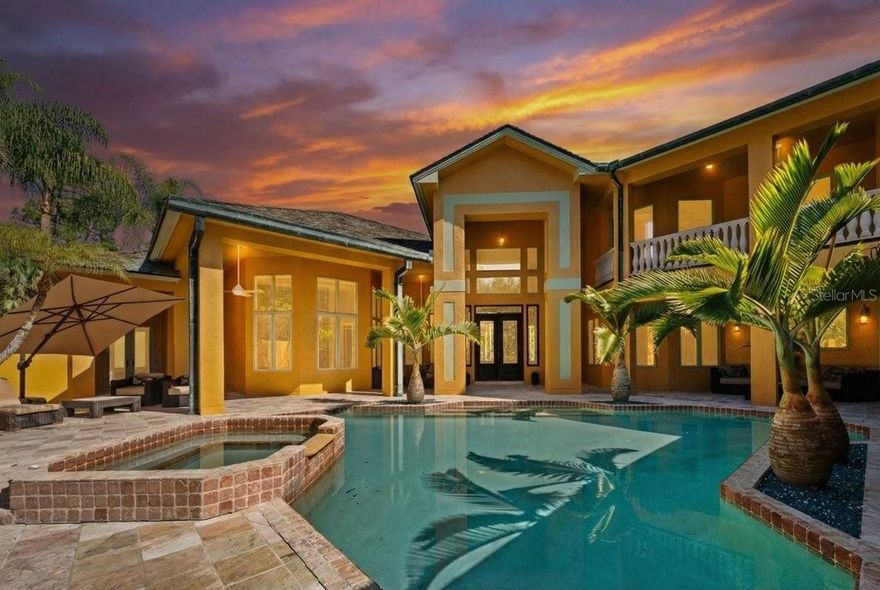 One or more photo(s) has been virtually staged. There are homes you visit, and then there are estates that quietly feel as though they’ve been waiting for the right owner to arrive. Strategically positioned and priced below market value, this Mediterranean-inspired residence presents a rare opportunity for the discerning buyer—one who understands that true luxury is not only measured in finishes, but in how a home makes you feel. Set behind lush tropical landscaping on three private acres, surrounded by over 150 Palms, the approach alone begins to slow your pace. A private road draws you inward, where filtered sunlight and soft coastal breezes replace the outside world. By the time you reach the brick-paved circular drive, it feels less like a showing and more like the start of a permanent escape. Spanning approximately 7,100 square feet, the two-story residence balances scale with serenity. Inside, 15-foot ceilings and timeless architectural details create an airy openness, while natural light pours through oversized windows and glass doors. Travertine floors reflect the warm afternoon glow, maintaining a seamless connection between indoors and out. Each space is thoughtfully designed—not just for function, but for the experience of living well. The home offers four bedrooms and four bathrooms, along with a private office, media room, parlor, dining room and dinette, and a versatile flex space. Additionally, there is a library and office which can easily convert into an additional ensuite bedroom, allowing the home to evolve with its owner. Even your four-legged companions are considered, with a private doggy suite complete with its own viewing area; because here, every detail matters. The main living areas naturally transition outdoors, where Southwest Florida living reveals itself fully. A 44-foot covered patio extends from the primary suite and living spaces, opening to a heated saltwater pool and spa that feels like a private resort. A separate one-bedroom casita with its own living area enhances the sense of privacy and flexibility. Mornings begin with coffee beneath swaying palms, afternoons stretch beside the pool, and evenings settle in with warm Gulf breezes and painted skies. Upstairs, a hardwood maple staircase leads to additional living areas, continuing the home’s quiet refinement. A slate roof and copper patina gutters add timeless character, while an indoor slate fountain with customizable lighting introduces a calming, spa-like presence. Despite its peaceful setting, the estate is just fifteen minutes from Naples’ renowned beaches, where turquoise waters and powder sand define the coastline. Here, life becomes a seamless blend of barefoot mornings, waterfront afternoons, and elegant evenings—an effortless transition for those accustomed to luxury living up north, now reimagined in a year-round coastal setting. With no HOA or deed restrictions, the property offers rare freedom. Additional features include a three-car garage, dedicated microgreen growing space, an outdoor area ideal for a gazebo or firepit, and a full-house Generac generator, providing comfort and peace of mind. At $2,999,000, this is not simply a home priced to sell, it is an invitation to trade cold seasons for endless sunshine, to own a residence that feels like a private escape every day, and to place your own signature on an already exceptional canvas. This is Naples living at its most refined. Where every arrival feels like a getaway, and every day feels like the life you’ve always imagined.