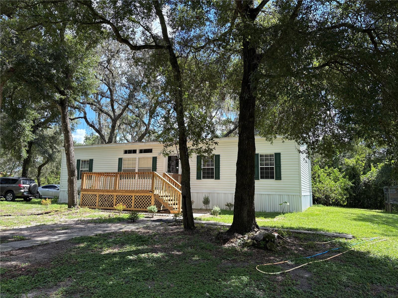 Your Dream Retreat Awaits! Escape to paradise with this stunning 2016 Live Oak home, offering 1,560 sq ft of luxurious living space with 4 bedrooms and 2 bathrooms, perfectly nestled on a sprawling 5-acre lot enveloped by majestic mature oak trees. This isn’t just a home, it’s a lifestyle, blending serene country living with modern convenience, especially with the exciting new development unfolding in nearby Ridge Manor. Why settle for a cookie-cutter home when you can own 5 acres of tranquil beauty, providing a cool, shaded haven during these warm days? Step outside to a welcoming front porch featuring a sturdy wooden deck and stairs, ideal for unwinding or hosting gatherings, surrounded by vibrant crepe myrtle lining the fence, a mature, producing tropical beauty peach tree, an olive tree, and a couple of sour orange trees perfect for crafting your own mojito. A newly laid paver walkway, freshly landscaped with hummingbird-friendly Texas sage and firebush to attract the regular visitors, and adorned with a mature rose bush, guides you to the entrance, enhancing the property’s curb appeal with natural elegance. Inside, indulge in brand-new carpet in the bedrooms, elegant wood laminate floors throughout the main living areas, and a kitchen transformed with high-end upgrades: a new Whirlpool 1.9 cu. ft. Over-The-Range Microwave with Sensor Cooking, a new GE 55 dBa Front Control Dishwasher with Dry Boost and Piranha Hard Food Disposer for quiet efficiency, a brand-new Kraus Bellucci Drop-in 33-in x 22-in Quartz farm apron single bowl Workstation Kitchen Sink, and a Kraus Bolden Black Single Handle Deck-mount Pull-down Kitchen Faucet with Sprayer. The 448 sq ft cedar workshop awaits your personal touch, easily wired for a custom man cave, while a separate back well—needing only a pressure tank and setup—offers potential for private irrigation. The front 1.5 acres are securely fenced with newer fencing, complemented by a front gate with a mule ready to be hooked back up for added security or livestock. Zoned agricultural, this property is a haven for farming or livestock, with no flood insurance required, Stay powered with the home’s generator wiring, complete with an included generator, and enjoy predictable utility costs serviced by Withlacoochee River Electric Cooperative, where the seller confirms bills consistently run around $157 per month, never exceeding $180.