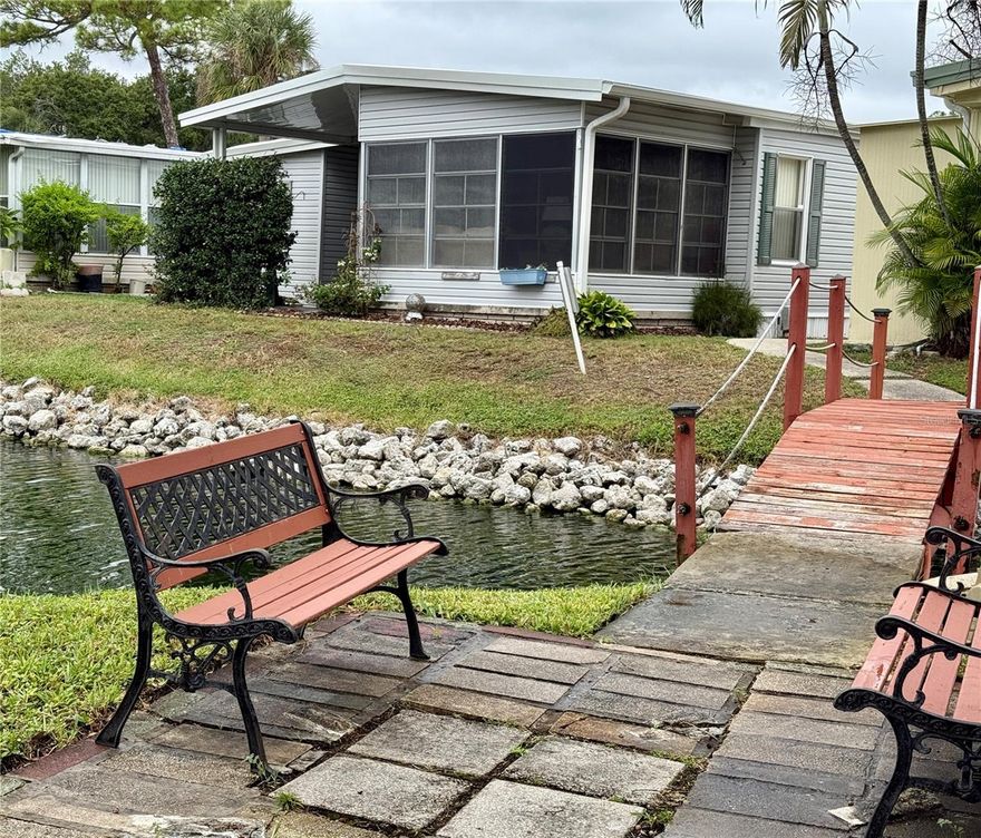 LOCATION with a VIEW! This Home is Located Directly on the Bank of the Community Pond. A Sweet Tiny Island Sitting Spot is Right Out the Back Door, Accessible by a Cute Arched  Boardwalk...this is the Charming View from the Living Room and Enclosed Back Porch. A Jasmine Protected Outside Patio, also Facing the Pond Abuts the Enclosed Porch. A Turtle / Comorant Landing is Right off the Back Yard...No Back Neighbor. The Interior is Equallly Nice...Sliders from the Living Room Open to the Back Porch * The Dining Room L Off of the Living Room and Ajacent to the Kitchen has a Lighted Built-in Hutch and a Window View of the Pond. * The Roomy Kitchen has: Quartz Counter Tops * Glass Tile Backsplash * Stainless Appliances * In the Den / 2nd Bedroom is a Built-in Desk with Shelves, Built-in Drawers with Hanging Space and a Double Closet. The Included Futon Makes for an Easy Conversion to a Guest Room. * Hall Bath is a Tub / Shower Combination * Primary En-suite Bath is a Shower Bath. * The Spacious Primary Bedroom Offers a Large Walk-in Closet Plus a Linen Closet and En-Suite Bath. This Home is Being Sold Furnished As Seen Including the Stackable Washer & Dryer. * ROOF NEW in 2024 * A/C INCLUDING ALL NEW DUCT WORK and NEW THERMOSTAT NEW in 10/2025! * Lake Rich Village is Convienient to Shopping and a Quick Drive to the Beaches. * Over 55 * No Pets * No Renting