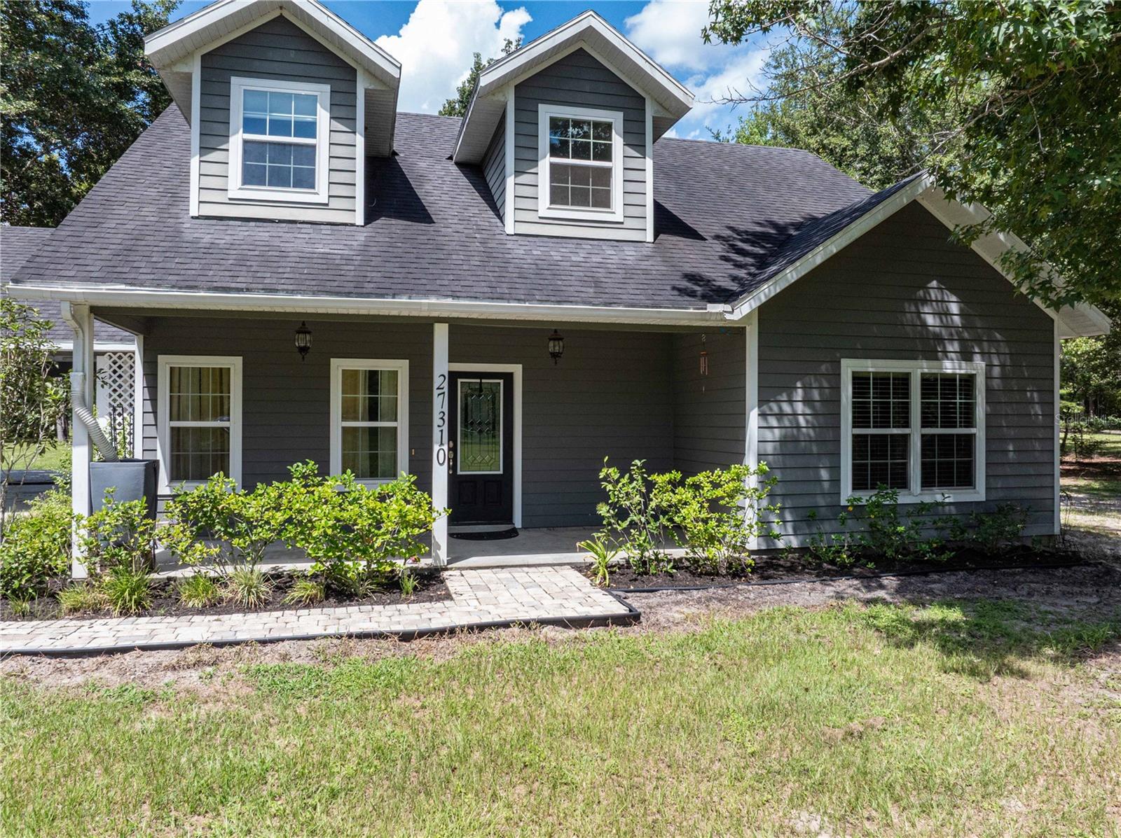 Discover privacy and comfort in this beautiful 2-story home on 5.77 acres in Alachua. With 3 bedrooms, 3.5 bathrooms, and an office, this home offers both space and versatility. Each bedroom has its own private en-suite bath, making it perfect for family and guests alike. The foyer features 2nd story dormer windows that welcome you with natural light and leads into the open-concept great room, kitchen, and dining area. The kitchen is designed for both style and function, featuring granite countertops, newer GE slate stainless steel appliances, and a large eat in bar. A spacious laundry room with cabinetry and a convenient half bath for guests complete the downstairs living space. The primary suite is a true retreat with his-and-hers walk-in closets and a luxurious bath that includes a large walk-in shower with dual shower heads. Additional highlights throughout the home include granite countertops in all bathrooms, a water filtration system, gutters on the front of the home and a gas tankless water heater. Outdoor living is just as inviting with a covered back patio that overlooks the peaceful lot accented by mature trees and blooming crepe myrtles and a custom dog house with running water. A detached metal building with a large lean-to offers plenty of room for storage, equipment, or projects, while the 2-car carport provides everyday convenience. This home combines rural privacy with modern comfort, all within a short drive to downtown Alachua, Gainesville, and area amenities.