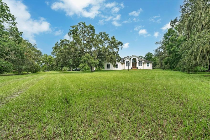 Welcome to this stunning single-story estate, ideally nestled on 6.93 acres of peaceful, tree-lined land, offering privacy, space, and timeless Florida charm. The striking exterior, with arched windows, a grand columned entry, and natural surroundings, sets the tone for the comfort and elegance within.

Step inside to a bright, open-concept layout with tile flooring throughout, creating a seamless flow from room to room. The formal living room welcomes you with abundant natural light, vaulted ceilings, and a gas fireplace, perfect for cozy evenings.

The heart of the home is a gourmet kitchen, featuring premium appliances including a Viking oven and Sub-Zero refrigerator, complemented by generous cabinetry and countertop space—ideal for both everyday cooking and entertaining.

Retreat to the luxurious primary suite, which includes a double-sided gas fireplace that connects to a spa-inspired bathroom, creating a peaceful, retreat-like atmosphere.

Across the home, you'll find three additional bedrooms and two full bathrooms, offering ideal separation for family or guests. A dedicated study and formal dining room provide functional, flexible living spaces for working from home and entertaining with ease.

Step outside to enjoy the outdoor kitchen area, perfect for weekend grilling, al fresco dining, and hosting gatherings in your private, scenic backyard.

The expansive 6.93-acre lot offers ample room for recreation, gardening, livestock, or future additions. With no HOA, you’ll enjoy true freedom and flexibility, and the ag-friendly zoning allows for livestock—bringing your country-living dreams to life without sacrificing convenience.

Nature lovers will especially appreciate that this property is located less than 2 miles from Alderman Ford Conservation Park, where you can hike, fish, canoe, bird watch, picnic, and even camp. It’s the perfect extension of your own outdoor paradise, just minutes away.

Located in a highly desirable area, the home is zoned for top-rated middle and high schools, making it an ideal fit for families seeking excellent education in a tranquil, upscale setting.

With two gas fireplaces, tile flooring throughout, high-end kitchen finishes, a dedicated study, formal dining room, outdoor kitchen, and access to nearby nature preserves, this home offers a rare opportunity to own a luxurious yet practical estate on nearly 7 acres in a prime Florida location.