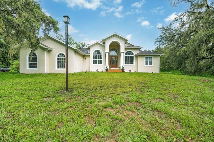 Welcome to this stunning single-story estate, ideally nestled on 6.93 acres of peaceful, tree-lined land, offering privacy, space, and timeless Florida charm. The striking exterior, with arched windows, a grand columned entry, and natural surroundings, sets the tone for the comfort and elegance within.

Step inside to a bright, open-concept layout with tile flooring throughout, creating a seamless flow from room to room. The formal living room welcomes you with abundant natural light, vaulted ceilings, and a gas fireplace, perfect for cozy evenings.

The heart of the home is a gourmet kitchen, featuring premium appliances including a Viking oven and Sub-Zero refrigerator, complemented by generous cabinetry and countertop space—ideal for both everyday cooking and entertaining.

Retreat to the luxurious primary suite, which includes a double-sided gas fireplace that connects to a spa-inspired bathroom, creating a peaceful, retreat-like atmosphere.

Across the home, you'll find three additional bedrooms and two full bathrooms, offering ideal separation for family or guests. A dedicated study and formal dining room provide functional, flexible living spaces for working from home and entertaining with ease.

Step outside to enjoy the outdoor kitchen area, perfect for weekend grilling, al fresco dining, and hosting gatherings in your private, scenic backyard.

The expansive 6.93-acre lot offers ample room for recreation, gardening, livestock, or future additions. With no HOA, you’ll enjoy true freedom and flexibility, and the ag-friendly zoning allows for livestock—bringing your country-living dreams to life without sacrificing convenience.

Nature lovers will especially appreciate that this property is located less than 2 miles from Alderman Ford Conservation Park, where you can hike, fish, canoe, bird watch, picnic, and even camp. It’s the perfect extension of your own outdoor paradise, just minutes away.

Located in a highly desirable area, the home is zoned for top-rated middle and high schools, making it an ideal fit for families seeking excellent education in a tranquil, upscale setting.

With two gas fireplaces, tile flooring throughout, high-end kitchen finishes, a dedicated study, formal dining room, outdoor kitchen, and access to nearby nature preserves, this home offers a rare opportunity to own a luxurious yet practical estate on nearly 7 acres in a prime Florida location.