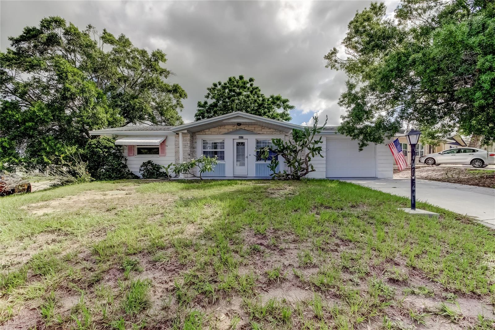 Vintage Florida Home...This solid structure 2 bedroom, 2 bath, 1052 square foot, 1 car garage home is nestled on a huge corner lot in a serene, quiet community with it's convenience and curb appeal. Step inside and discover a well-maintained interior with beautiful nostalgic Terrazzo flooring throughout, offering easy care and durability with spacious living areas creating a welcoming atmosphere, perfect for both everyday living and entertaining. The kitchen is functional with fairly good appliances, plenty of storage and counter space, ideal for meal preparation and family gatherings. The two generous bedrooms provide plenty of space for relaxation both with ceiling fans and real cedar wood closets. Other features include newer windows throughout, no Flood zone, no HOA, no CDD, air conditioned sun room and fully enclosed patio perfect for unwinding with family & friends, powder blue retro style full bath, full bath in the garage provides added convenience, new septic coming July 2025. The fenced backyard is a private oasis ideal for pets, gardening, or simply enjoying the outdoors in peace. The oversized 1 car garage is an added bonus, not only providing valuable storage space but your very own workbench also fully equipped with tools and miscellaneous items that will be included with the sale to help you maintain and enjoy your new home. A short drive to Anclote State Park, Tarpon Springs Sponge Docks, Sunset Beach and Fred Howard Park