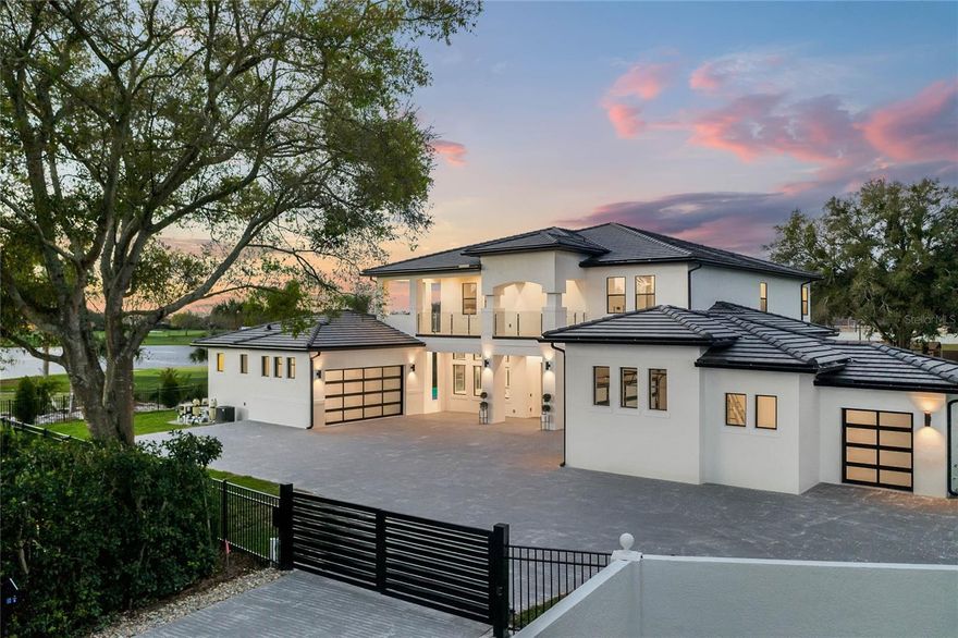 Welcome to 11 Bay Hill, perfectly positioned on the 11th hole with 253 feet of breathtaking golf and water frontage overlooking the world-famous PGA course. This newer custom contemporary estate is an architectural showpiece, privately tucked away on a cul-de-sac with a long private drive and gated entry. Nearly two years in the making, the home was thoughtfully designed to capture sweeping panoramic views while offering exceptional comfort and privacy. From the moment you enter, the large porcelain tiles makes a striking statement, meticulously installed to complement the home’s custom design. Soaring 22-foot ceilings and 9-foot sliding glass doors fill the interior with natural light. At the heart of the home, a double-island chef’s kitchen opens seamlessly to the family room and features Sub-Zero and Wolf appliances, along with an impressive 534-bottle wine cellar. Throughout, flawless Level 5 finishes highlight the extraordinary craftsmanship. The main-level primary suite is a true retreat, complete with a private sitting area and a spa-inspired bath. Outdoors, an expansive living area sets the stage for unforgettable sunsets, centered around a glass-mosaic, infinity-edge heated pool with a 360-degree spa and dramatic fire bowls. 11 Bay Hill is a rare, one-of-a-kind golf-front estate and a once-in-a-lifetime opportunity to own a property that will be admired for years to come offering an exceptional lifestyle from the moment you pass through the gates.