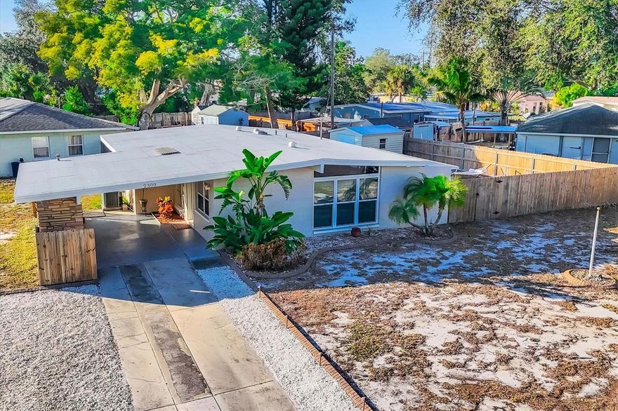 Charming mid-century modern home located on an oversized corner lot with thoughtful updates and fantastic outdoor living. This 3-bedroom, 2-bath home features a bright great-room layout with polished terrazzo floors and warm mid-century character throughout. The updated kitchen includes French-cream cabinetry, solid-surface counters, ceramic backsplash, and stainless steel appliances, with an adjoining dining area and a flexible all-seasons Florida sunroom. Major improvements were completed in 2019, including a new roof, updated plumbing, and newer A/C.  Most recently (2025) the home has new exterior paint, new front windows, new backyard fence (2024) and a new garbage disposal—making this home truly move-in ready. The fenced in backyard is ideal for relaxing or entertaining with a fire pit, paver patio, and plenty of room for pets. Storage is abundant, with a backyard shed that stays, plus covered storage under the carport. Additional features: optional $10 HOA, access to the Bayshore Gardens recreation center with pool, park, marina and boat ramp, home is NOT located in a flood zone, and conveniently located near shopping, dining, and the Gulf beaches. This lovingly maintained mid-century home is ready for its next owners. Set up your showing today!