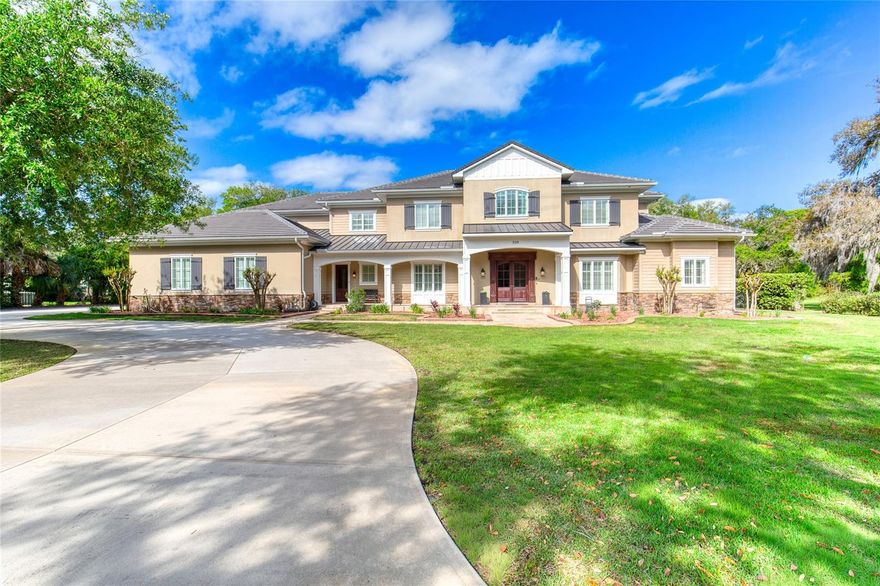 Timeless elegance discreetly nestled in the heart of Ormond Beach! 
This exceptional 5-bedroom, 6 bathroom estate, complete with a 4-plus-car garage & private saltwater pool & spa, offers both convenience & seclusion. Situated in a tucked-away community of one-acre parcels just minutes from shopping, dining, cultural venues & the beach, this home comes with the option to purchase an additional adjacent acre to further enhance privacy. 
Constructed in 2009 with uncompromising attention to quality, no expense was spared in creating this enduring & sophisticated family estate. Encompassing just under 10,500 square feet of combined indoor & outdoor living space, the residence is ideally suited to accommodate a growing family or multi-generational household.
The oversized 4-plus-car garage features 2 double-width doors, one of increased height to accommodate a recreational vehicle or boat.
The moment the residence comes into view, its circular driveway, majestic oak trees, stone-lined raised landscape beds, & stone-tiled front porch with stacked-stone apron set a tone of grandeur. Additional architectural details including the metal & tile roof, framed windows, shiplap siding, decorative millwork, & stately double wood & glass entry doors further underscore the home’s refined character.
Upon entry, a formal foyer welcomes guests with the main staircase to the right & the formal dining room to the left. Rich Brazilian walnut hardwood flooring extends throughout. Ahead, the impressive great room featuring soaring 23-foot ceilings & a gas-burning fireplace serves as the heart of the home. Double French doors flanking the fireplace open to a covered rear lanai overlooking the private 18' x 27' saltwater pool & 8-person waterfall spa.
The chef’s kitchen is appointed with bull-nose granite countertops, Monogram appliances including a four-burner gas range with center grill & convection oven, 2 dishwashers & an expansive 9' x 6' walk-in pantry. The large center island incorporates a prep sink, warming drawer, one dishwasher & bar seating. The outdoor summer kitchen provides a 2nd cooking arena.
Adjacent to the eat-in kitchen is a formal game room featuring a fully equipped bar with beverage cooler, ice maker & dual taps. This room is home to a full-sized pool table, tabletop shuffleboard, game table, & large flat-screen television. Built-in cabinetry houses the home’s comprehensive security & audio systems.
The main level also includes the primary suite with French doors leading to the outdoor living space. The en-suite bathroom features a glass-enclosed walk-in shower, soaking tub, dual vanities, & 2 spacious walk-in closets with custom organizers. Additional main-floor amenities include an office, laundry room, service entrance, & 2 half baths.
The upper level offers 4 additional bedrooms, each with an en-suite bathroom & custom cabinetry, a 2nd laundry room, an art room/library, & an 2nd great room with 2 walk-in closets potentially suitable as an additional primary suite. This level is also home to an expansive covered balcony with sweeping views of the backyard.
Notable features throughout the home include volume ceilings with decorative tray details, recessed lighting, plantation shutters, a smart leak detection system, programmable thermostats, remotely controlled pool/spa equipment, & whole-house generator. Nearly every room is equipped with a flat-screen TV including the outdoor living area above the cozy wood-burning fireplace.