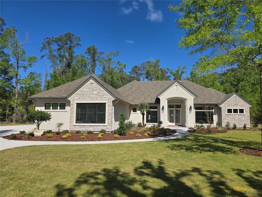2026 Parade of Homes! Introducing this breath taking home crafted on a beautifully wooded 1.56 acre lot in The Reserve at Millhopper. Meticulously designed and constructed by Barry Bullard Homes, this remarkable residence spans 3735 square feet, offering a seamless open concept floor plan complemented by captivating glass elements throughout. With a thoughtfully planned layout, this home presents 4 bedrooms with 4 ensuite bathrooms and an additional guest half bath, a study, and a versatile flex room with a wet bar. The great room stands out with 12” ceilings with decorative wood beams . A gas fireplace with a custom precast stone surround creates a cozy ambiance, while built-in cabinets provide both functionality and style. The heart of the home is every culinary enthusiast's dream kitchen. It boasts a sprawling island and top-of-the-line KitchenAid package including 36” Dual Fuel range, custom made metal vent hood, 36” counter depth refrigerator, dishwasher, microwave drawer, and wine refrigerator. A large walk-in  butler’s pantry with prep sink and generous storage shelving completes the kitchen package. The kitchen great & dining rooms extend seamlessly outdoors through a stack of sliding glass doors, leading to a spacious outdoor entertaining area. This enchanting patio is fully paved and offers a beautiful pool with a sun shelf, and a mesmerizing water feature. A large lanai features with electric powered roll down screens features a summer kitchen with a built-in grill and sink. The master suite serves as a true sanctuary, encompassing two walk-in closets, dual sink vanity, a sizable walk-in shower, and a freestanding soaking tub for indulgent relaxation. Energy efficiency takes center stage in this home, thanks to its cutting-edge features including spray foam insulation, tankless hot water heaters, electric heat pump HVAC system split into 2 zones for high-efficiency heating and cooling, LED recessed cans, and vinyl insulated low E windows. Elevating the interior to new heights, this residence showcases upgraded finishes throughout. Luxury Vinyl Plank flooring graces every room except the bathrooms, clean modern interior trim adds a touch of elegance, cove crown molding adorns the common areas and master suite. Enhanced plumbing and lighting fixtures further amplify the home's luxurious appeal. The laundry center offers convenience with its practical folding top, and a 3-car garage adds ample space for vehicles and storage. Externally, the home is adorned with smooth finish stucco and decorative stone accents. The property is situated on a meticulously landscaped 1.56-acre lot. In its entirety, this newly constructed masterpiece within The Reserve at Millhopper epitomizes the pinnacle of luxury living, showcasing remarkable design features and modern conveniences that cater to your every desire.