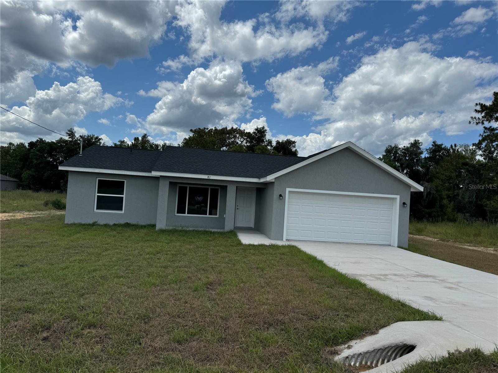 This enchanting new abode is situated on a corner lot that offers a larger piece of land! As you step into this exquisite, brand-new 3 bedroom, 2 full bath, 2 car garage home in Ocklawaha, the air is filled with a fresh and invigorating scent, just like new! The interior boasts a blend of light and dark grey LVP flooring, creating a modern and sharp ambiance. The open floor plan seamlessly flows into the living room, adorned with stunning bright white shaker cabinets and a kitchen space overlooking the backyard. The kitchen is a sight to behold, featuring stainless steel appliances, a glass top stove, dishwasher, microwave, and a refrigerator with side by side water and ice dispenser, all complemented by gray, black, and white granite countertops. Privacy is guaranteed with the split plan layout, especially in the master bedroom with its oversized walk-in closet and a master bathroom equipped with a stand-up shower, his & her sinks, and matching white shaker cabinets. The guest bathroom, located on the opposite side of the home near the other two bedrooms, offers a tub/shower combo and the same elegant white shaker cabinets with granite countertops. Soft close cabinets throughout the house add a touch of sophistication. The location of this home within the subdivision is truly remarkable, offering a serene and picturesque setting. Step outside and experience tranquility and peace, with a clear view of the starlit sky at night. The spacious outdoor area is perfect for entertaining guests with activities like badminton, croquet, or golf. You could even set up a swing for the little ones or bring a fire pit for cozy evenings. Conveniently close to amenities yet nestled in the countryside, this home features a charming front porch where you can enjoy your morning coffee and plan your day. With a septic system and well in place, say goodbye to water bills and hello to energy efficiency. Rest assured, this home is a true gem waiting to be discovered and cherished. Be the first to make it yours and create unforgettable memories in this romantic haven.