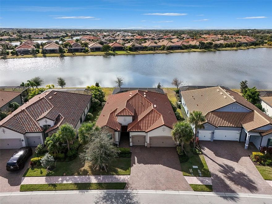 Rare opportunity to own a breathtaking home in Country Club East, a premier gated community of Lakewood Ranch and one of the area’s most sought-after neighborhoods. Designed with the sophistication of a professionally modeled residence, this impeccably appointed home on a  homesite blends refined craftsmanship with effortless indoor–outdoor living, all set against tranquil lake views and stunning sunset backdrops.

An open-concept floor plan is enhanced by porcelain  tile flooring throughout, tray ceilings, crown molding, and architectural detailing, creating a cohesive and timeless interior. The expansive great room centers around a custom-designed media wall featuring a dramatic 120-inch fireplace with mantel and remote control. This striking centerpiece accommodates an 85-inch wall-mounted television and is accented by illuminated floating shelves on either side.

The open layout continues into the dining area with decorative chair rail detailing and remote-controlled designer window treatments. The adjacent chef’s kitchen is both elegant and functional, featuring GE Profile stainless steel appliances, a built-in oven and microwave, gas cooktop, upgraded sink and faucet, walk-in pantry with custom wood shelving, and an oversized island ideal for entertaining and everyday dining.

Disappearing sliding glass doors extend the living area onto the lanai, where stone pavers, a fully equipped outdoor kitchen with refrigerator, Coyote barbecue grill, stone backsplash, and vent hood create an inviting setting for outdoor living. A heated pool and spa complete this exceptional space, offering peaceful lake views and unforgettable sunsets.

Designer touches continue throughout the home, with the primary suite serving as a private retreat featuring direct lanai access, tray ceilings, lighted wall switches, remote-controlled window treatments, and a custom ceiling fan. The en-suite bath includes dual vanities, an expansive walk-in shower with dual showerheads, and two walk-in closets with wood shelving.

Two additional bedrooms provide comfort and privacy, each with access to separate baths, including one en-suite bath with a glass shower enclosure. Both bedrooms feature ceiling fans and lighted wall switches. The study/den offers flexible living space and guest accommodations, showcasing designer built-ins with a dual desk and a hidden Murphy bed seamlessly integrated into custom bookcases. A well-appointed laundry room features a built-in ironing board and wall-mounted drying rack.

This home is a rare offering where thoughtful design, luxury finishes, and indoor–outdoor living come together in perfect harmony.

Residents of Country Club East enjoy exclusive access to The Retreat, a private amenity center with a fitness center, resort-style and lap pools, and a social clubhouse, along with scenic walking and biking paths. Optional membership to the Country Club at Lakewood Ranch includes championship golf, tennis, fitness centers, and access to the Lodge bar and restaurant. Conveniently located near shopping, dining, medical facilities, and world-class Gulf Coast beaches, Country Club East offers an exceptional lifestyle of luxury and recreation