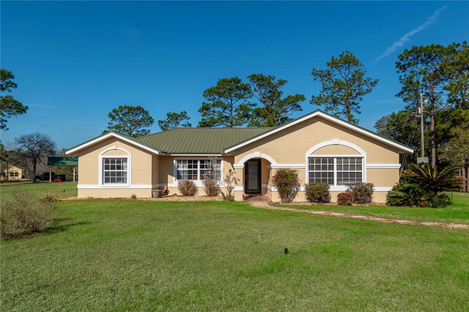 Nestled in the tranquil Fox Grove Farms neighborhood, this charming 3-bedroom, 2-bathroom home offers the perfect balance of privacy and rural charm—all while being just a short drive from Ocala, Gainesville, and Dunnellon! Set on a corner lot with 5.3 acres of fenced and gated land zoned Agricultural/Rural Residential, this property is well-suited for those seeking a peaceful retreat with the potential for a mini horse farm. Offering just over 1,800 sqft of space, the interior of the home features luxury vinyl flooring throughout that complements the home’s tall ceilings and abundant natural light. The large kitchen is equipped with lots of cabinet storage, stainless steel appliances, and a spacious breakfast nook, all located adjacent to the formal dining area for easy entertaining. Each bedroom is warm and inviting, though the primary suite is a real gem that includes a large walk-in closet with a shelving system and a private en-suite bathroom with dual vessel sinks and a glass-door walk-in shower. Towards the back of the home is a spacious family room that showcases tall wooden ceilings, large windows for stunning views of the surrounding property, and a cozy gas-burning fireplace. Outside, the backyard provides a quiet oasis with a sparkling above-ground pool and a raised pool deck with plenty of space for seating. Established on the property is a pole barn with a storage area/workshop– a fantastic option for those considering the option to fully convert this estate into a functioning horse farm. Fox Grove Farms is a quiet equestrian-friendly neighborhood that is perfect for riding on or off property. With Goethe State Forest just minutes away for horseback riding, hiking, and wildlife watching, plus Rainbow Springs State Park nearby for kayaking and swimming, outdoor enthusiasts will find endless opportunities for adventure. If you’re searching for a spacious country retreat with modern amenities and incredible outdoor access, this property is a true must-see!
