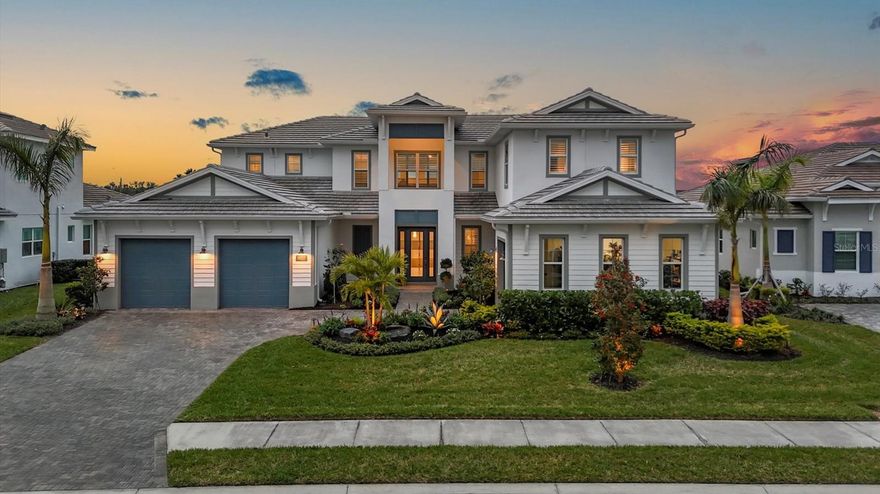 This custom-built lakefront estate in The Isles at Lakewood Ranch offers breathtaking water views, four bedrooms plus a versatile bonus room with an en-suite bath that could serve as a fifth bedroom, loft, office, 5.5 baths and nearly 5,000 square feet of opulent living space. Meticulously landscaped grounds and a split three-car garage welcome you. Enter through a custom glass front door to find exquisite porcelain tile flooring throughout the main living areas, enhancing the home’s refined elegance. Soaring 20-foot tray ceilings, custom plantation shutters, designer lighting and abundant natural light elevate the two-story living area, featuring a custom-built entertainment center designed to enrich your living experience. The chef’s kitchen is a culinary masterpiece, equipped with top-tier appliances, a gas stove, quartz countertops, a spacious island with breakfast bar seating and an expansive pantry. A reverse osmosis system ensures pristine water. The kitchen flows seamlessly into the grand living and dining areas, ideal for entertaining. The generously proportioned primary suite is a serene retreat with a tray ceiling, custom plantation shutters, two built-in walk-in closets and a spa-inspired en-suite bath featuring dual vanities, a soaking tub, an oversized shower with dual shower heads and additional closets for maximum storage. Downstairs, you’ll also find a refined office, a private guest suite with an en-suite bath, a mudroom with custom built-ins and a beautifully appointed laundry room with cabinetry. Upstairs, the open loft overlooks the grand living area below, complemented by two additional guest suites with en-suite baths, as well as a bonus/media room suite that could also serve as a fifth bedroom. The outdoor living space is a resort-style lanai with a tongue-and-groove wood ceiling, a heated saltwater pool, spa, fountains, and an expansive outdoor kitchen with custom cabinetry and stainless-steel backsplash, all offering spectacular views of the lake. Additional features include a whole-house generator, water softener, in-wall pest system, designer lighting and luxurious finishes throughout. The Isles at Lakewood Ranch offers world-class amenities, including a clubhouse, fitness center, resort-style pool, walking trails and tennis courts, along with top-rated schools, golf courses, parks, shopping, dining and easy access to Gulf Coast beaches. This home exemplifies unparalleled luxury living in Lakewood Ranch.