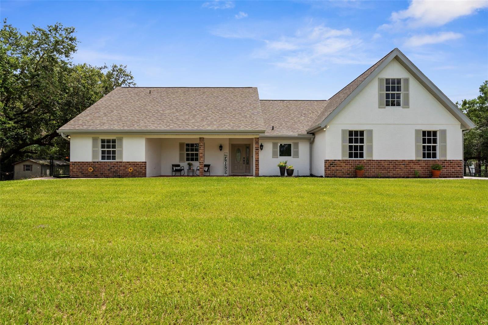 Welcome to 18355 State Road 62 in Parrish, Florida—a beautifully maintained and tastefully updated country farmhouse retreat nestled on 15.72 fenced acres, offering peaceful privacy, room to grow, and exceptional functionality.
This single-family home was built in 2003 and offers 2,723 square feet of living space with three bedrooms, two-and-a-half bathrooms, a formal dining room, a cozy fireplace in the main living area, a den or office flex space, and a 404-square-foot bonus room above the garage that serves as a perfect guest space, gym, or creative retreat. The two guest bedrooms are connected by a Jack-and-Jill style bathroom, providing an ideal private layout for family or visitors.
In 2023, all flooring throughout the home was replaced, and the kitchen was updated with new appliances. In 2025, the home's exterior received a full refresh including the removal of original siding, application of new stucco, and a vibrant white paint finish with light gray trim accents. The interior was freshly painted in 2025 as well and features new 5-inch baseboards and custom trim work around room entries. Mechanical updates include a new water heater in 2024 and split HVAC systems with exterior units installed in 2021 and 2022, and interior units installed in 2022. The home was pre-inspected by a licensed inspector, and the sellers have proactively addressed all noted major and minor discrepancies, giving future buyers peace of mind and confidence in the home’s condition.
Two doors lead from the living space to a private back patio, recently coated in a neutral epoxy finish, which opens to a fire pit area—ideal for relaxing under the stars. From the front porch, enjoy peaceful views of a tranquil pond that brings charm and serenity to your mornings. A standout feature is the paver brick sidewalk and matching brick-accented front porch, which enhances the curb appeal and blends seamlessly with the home's lower brick façade. In 2025, a new asphalt circle driveway was completed and lined with blooming crape myrtle trees to create a vibrant and welcoming entrance.
Additional features include a large covered workspace for tractors, vehicles, or equipment, a utility shed for additional storage, and an RV electrical hookup located on the back side of the property. The property is fully fenced and offers ample space for animals, gardening, or recreational use. Under current Manatee County land use regulations, this parcel allows for the construction of two additional structures, opening up endless possibilities for a guest house, barn, multi-bay garage, workshop, or even a private wedding venue. With large, mature oak trees providing a picturesque setting and existing power already available in that area of the property, it's the perfect foundation for a future event space or income-producing venue—pending appropriate permits and local approvals.
This home is conveniently located approximately 40 minutes from Sarasota-Bradenton International Airport and just under one hour to Tampa International Airport, with easy access to Parrish Community High School, Fort Hamer Park with boat ramp and recreational amenities, Little Manatee River State Park, Ellenton Premium Outlets, and the vibrant growth of North River Ranch with new shopping and dining options. With modern updates, timeless character, and unmatched acreage, this one-of-a-kind property is ready to welcome you home.