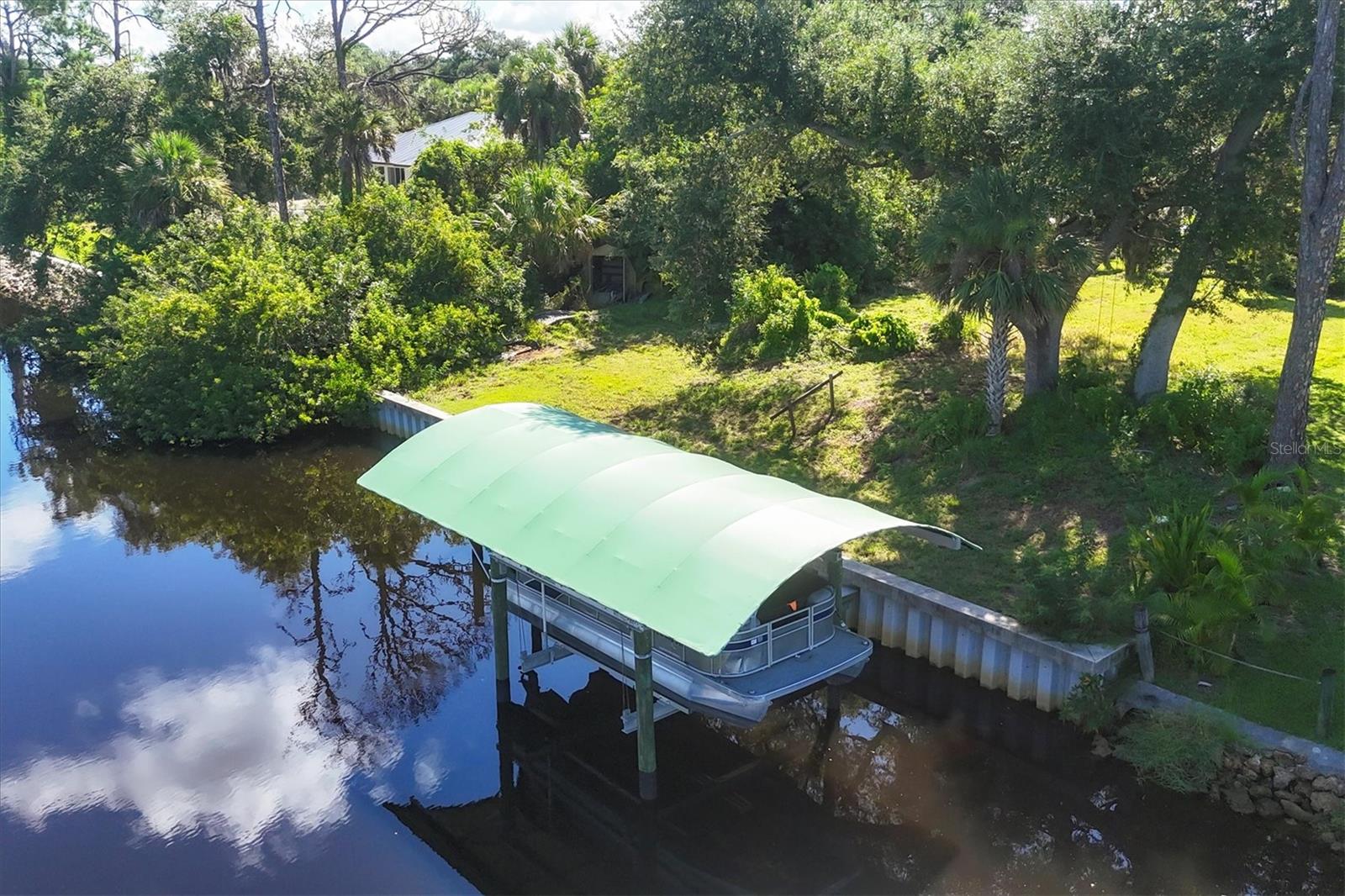 Boater’s Paradise with GULF ACCESS is only waiting for your imagination for the perfect Florida dream home. The Gulf, Charlotte Harbor and Myakka River are all within a short boat ride along the Apollo Waterway. This lot has been cleared, leaving beautiful oaks and palms and spectacular sunsets to decorate your new home, all without being located in a flood zone! Concrete seawall (80’), composite dock, and boat lift installed in 2021; lift canopy added in 2024. A temporary power pole has been installed for the boat lift and RV-hookup while building your custom slice of paradise. An additional 160 SqFt have been released from the canal easement to provide a seamless transition for a pool to connect to the boat dock. Spend your days fishing, boating or sipping your favorite beverage on the dock, watching the incredible sunsets. This property offers the perfect blend of tranquility and serenity, while being so convenient to excellent beaches, restaurants, shops, golf courses and endless outdoor adventures, in between North Port and Port Charlotte.