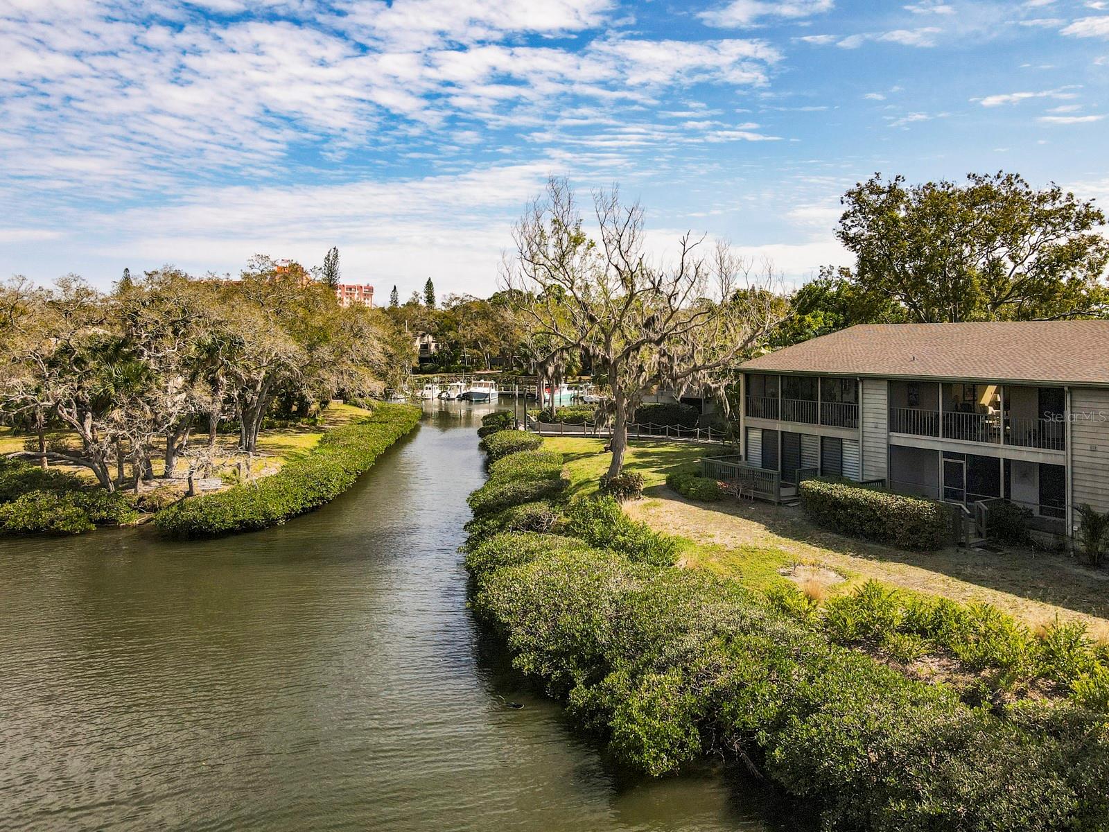 Discover serenity in this 2-bedroom, 2-bathroom second-floor condo with beautiful views of Clower Creek. Watch vessels gracefully navigate to and from the Pelican Cove Marina, creating a picturesque backdrop for your daily living. Enjoy the beauty of nature with views of the canal, making every day a visual delight. Immerse yourself in the local wildlife with frequent visits from pelicans, white herons, and other fascinating bird species. Experience a sense of grandeur with the sophisticated ambiance created by the cathedral ceilings in the living room and master bedroom as well as on the screened balcony. The height of the ceilings gives you a real sense of space. The clerestory windows in the living room allow light to flow through the condo. The kitchen boasts a modern aesthetic with white-on-white cabinets and appliances, complemented by cool bronze quartz countertops. Discover convenience with a plethora of pull-outs in the kitchen, providing ample storage space and easy access to essentials. The bathrooms have been tastefully updated with quartz countertops, new cabinets and new tile flooring. NEW hot water heater 2025, and NEW electrical panel 2025. Pelican Cove is an amazing hidden jewel in Sarasota! It is a well-manicured, lush tropical setting that is filled with opportunities to learn, create, and enjoy life! From pickleball to performing arts, Pelican Cove has it ALL! And the location can’t be beat, shopping, restaurants and beaches all within a close proximity, come take a look, you’ll never want to leave!