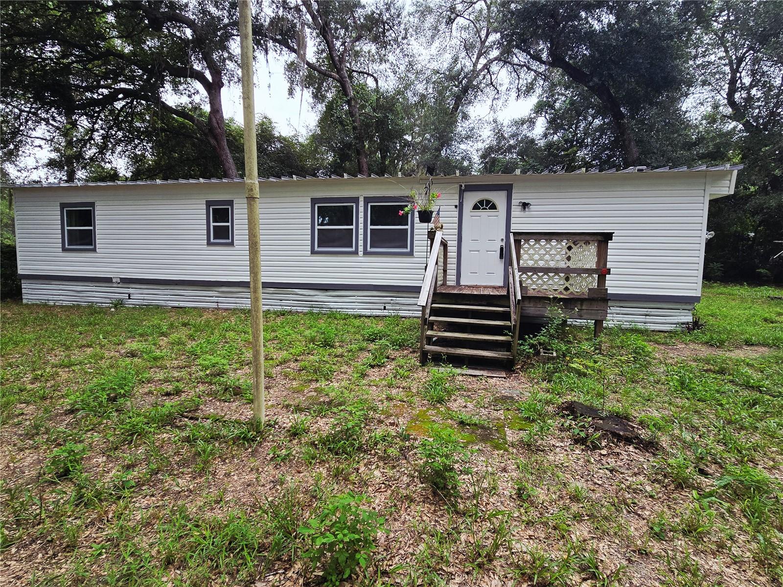 This cash-only single-wide mobile home is fully furnished and nestled in a wooded area. Located less than an hour from Daytona Beach and just 20 minutes from a Walmart. The property has been recently updated, featuring new windows, siding, and remodeled bathroom. Additionally, it includes two wall units for climate control and a shed equipped with 110 power.
