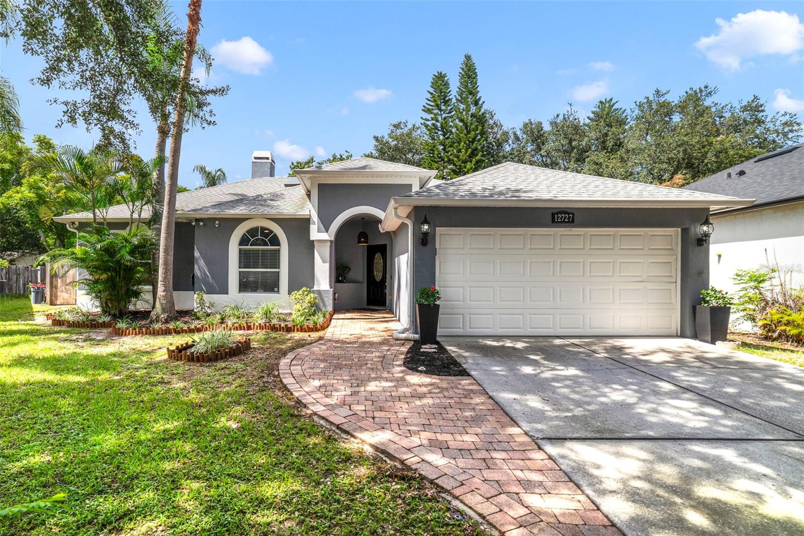 Major updates and a fantastic East Orlando location make this single story POOL HOME in the Woodbury Road Patio Homes community a true standout! You have a NEWER ROOF (2018), NEWER A/C (2021), POOL RESURFACED (2020), and the KITCHEN AND BATHROOMS have been tastefully REMODELED. The interior features UPDATED FLOORING - TILE & WOOD LAMINATE THOUGHOUT, double-pane windows, and 5” baseboards that elevate this home's fresh, modern appeal. The heart of the home is the beautifully updated kitchen boasting rich solid wood cabinetry, stone counters, decorative backsplash, must have STAINLESS STEEL APPLIANCES, pantry storage, a cozy island with bar seating, and a passthrough to the living room. A chic light fixture adds texture to the dining area, which flows seamlessly into the kitchen and out through sliding glass doors to the COVERED/SCREENED LANAI. In the family room a NEWER SKYLIGHT and a stacked stone WOOD- BURNING FIREPLACE sets a warm, inviting tone and French doors open directly to the pool area, blending indoor comfort with outdoor living! High ceilings and the many windows throughout let the natural light pour in. Tucked away off the family room, your generous PRIMARY SUITE delivers a large WALK-IN CLOSET with BUILT-IN STORAGE SYSTEM and a REMODELED EN-SUITE BATH featuring dual sinks, an oversized corner jacuzzi tub, and a separate tiled shower behind seamless glass. Two additional bedrooms share a second fully updated bath with a stylish, modern design. Outside, the private SCREENED POOL is “SALT READY” and comes with a child safety fence. The spacious lanai and fenced yard are perfect for relaxing, entertaining or enjoying Florida’s sunny weather. Nice landscaping, mature trees, and a paver walkway in the front add curb appeal from the moment you arrive. Also noteworthy; the plumbing has been partially updated, and some furnishings are negotiable – contact us for details! Located just minutes from Waterford Lakes Town Center, shopping, dining, golf, recreation, entertainment, and UCF, with easy access to SR 408 and SR 50 – you are truly central to everything East Orlando and beyond have to offer. Call today to schedule a tour and discover the possibilities on Woodbury Oaks Drive!