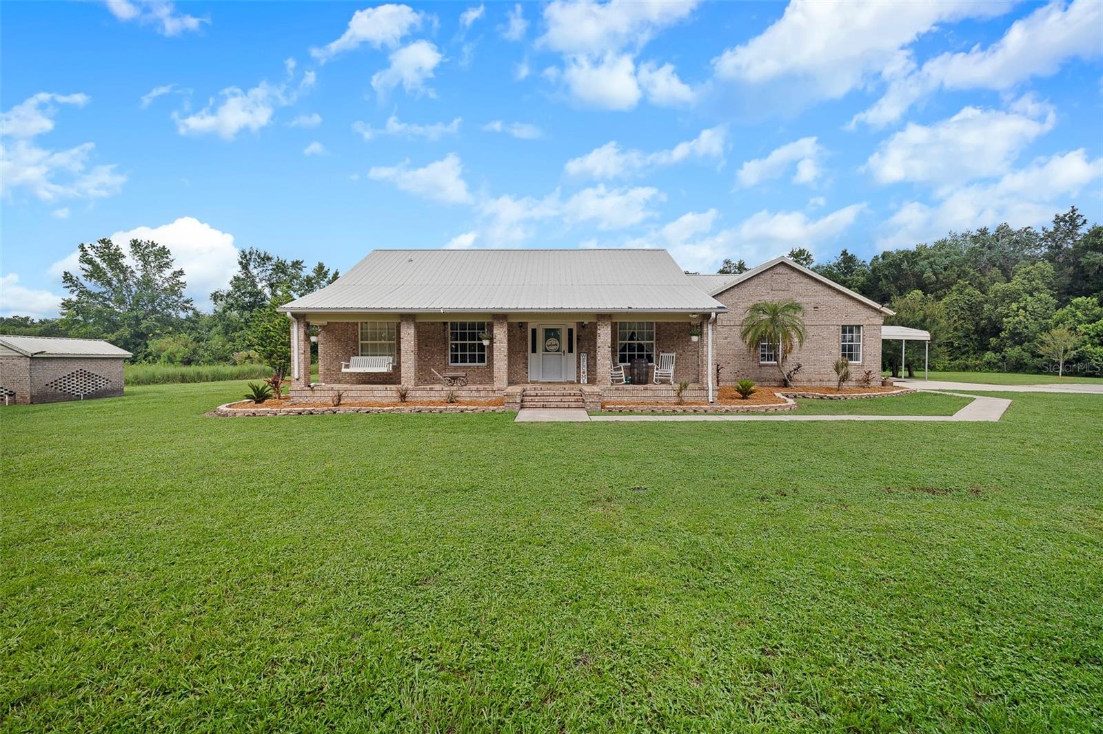Embrace the best of country living in this beautifully updated home set on 5 pristine acres in Bunnell. From the moment you arrive, the inviting front porch sets the tone for the warmth and charm found throughout. Step inside to discover a bright, open interior featuring fresh paint, updated lighting, and a welcoming layout designed for comfortable living. The kitchen and bathrooms are enhanced with sleek granite countertops, and the living room centers around a striking brick fireplace—perfect for cozy evenings. Outdoors, the property truly shines with a custom brick pizza oven, a functional shed, and a delightful chicken coop, creating an ideal setting for hobby farming or weekend entertaining. A propane-powered whole-house generator and hot water heater provide added peace of mind. Whether you’re relaxing on the spacious back porch or exploring your own private slice of nature, this property offers the perfect mix of modern convenience and rustic tranquility—ready for you to make it your own.