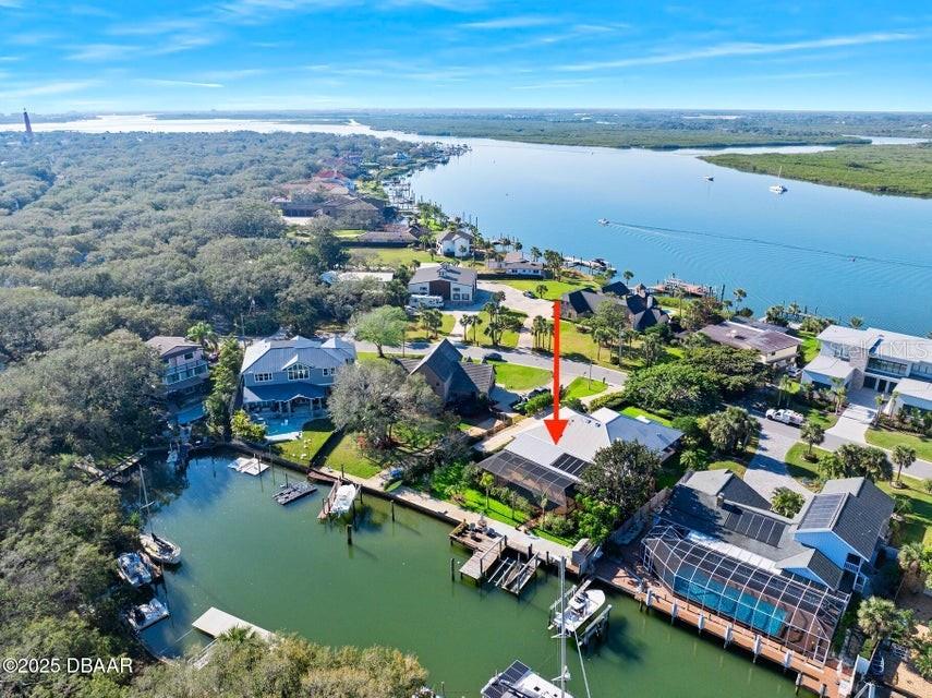 Fabulous custom waterfront pool home on coveted Ponce De Leon Circle here in South Ponce Inlet. Constructed to the highest standards in 2002 by highly regarded general contractor Jack McCarthy as his personal residence and subsequently renovated by his son, award winning custom home builder, Scott McCarthy, the home is being offered for the first time. Enter the property to experience the timeless beauty of British West Indies architecture where handsome beamed ceilings hover high above rich ceramic Saltillo floors in this warm and inviting island influenced atmosphere complimented by surrounding lush tropical gardens. The interior living spaces were designed to flow seamlessly with the vast covered outdoor living spaces ideal for open air living and entertaining. The spacious floor plan is situated around the beautiful kitchen with high end appliances set in handcrafted maple cabinetry appointed with lovely quartz tops.
A casual living room off the kitchen overlooks the green front lawn shaded by a most impressive banyan tree. The waterfront great room with fireplace opens through French doors onto the sprawling covered verandah that serves the owners as a large outdoor living room with additional dining space overlooking the very private pool with a subtle lagoon finish. Two of the four bedrooms rival each other for Primary Suite status. Both of these grand suites have dedicated access to the verandah, spacious walk in closets and gracious luxury baths with double vanities and cavernous showers. Two additional bedrooms share a bright and beautiful common bath. The home has a sizable indoor laundry room and walk in pantry plus two car side entry garage. Pride of ownership is apparent at every turn and the property has been maintained to high standards. As longtime Ponce Inlet residents, the owners chose this parcel of land for it's close proximity to the lighthouse parks, quaint waterfront restaurants and quiet stretch of beach, however the 110' of waterfront was truly ideal as it accommodated a 50' sportfish and two additional center console boats. This unique canal is lined with just 20 houses and is the closest protected deep water channel to the inlet and the open waters of the Atlantic. This is arguably the most sought after canal property in the county due to it's unique positioning for navigability coupled with being pinpointed in the center of one of the most beloved neighborhoods in our area. The property must be seen in person to experience the serenity of this quiet waterway and the towering oak hammock that shades the opposite shoreline here where pool and surrounding patios welcome the morning sun and enjoy the sea breezes from the Atlantic just a few blocks away.
