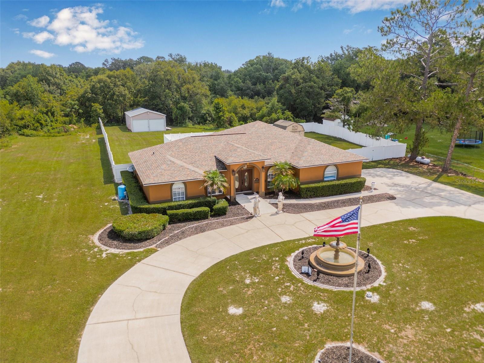 This one-story block home in San Antonio sits behind a white picket fence on a scenic road just 1.3 miles from I-75, offering peaceful surroundings with quick and easy access to the interstate. The home features a circular driveway, a solar-powered fountain, and an inviting open layout with crown molding throughout. The spacious primary suite is located at the back of the home with private access to the pool, a walk-in closet, and a luxurious en suite bathroom that includes dual vanities, a jetted tub, and a large walk-in shower. A split floor plan provides two additional bedrooms sharing a beautifully renovated bathroom, while a fourth bedroom across the hall can easily function as an office. The kitchen boasts granite countertops with counter seating, abundant cabinetry, and a breakfast nook overlooking the pool, all flowing seamlessly into the great room. French doors lead to a screened-in Florida room and a heated saltwater pool, surrounded by a vinyl fence for privacy and equipped with a surround sound system—ideal for entertaining. Beyond the pool, you’ll find a large(35x22) workshop with a 30-amp RV breaker, an additional shed for storage, and a spacious backyard with plenty of room to expand, plus a peaceful creek tucked behind mature trees. Additional features include travertine and tile flooring throughout (no carpet), high-end furnishings, a built-in safe, an attached 2-car garage with epoxy flooring, a Night Owl security system, and recent upgrades such as a new roof (2020) and AC (2018). Conveniently located near downtown Dade City, The Groves, Tampa Premium Outlets, local breweries, grocery stores, hospitals, and more. Call today for your private showing!