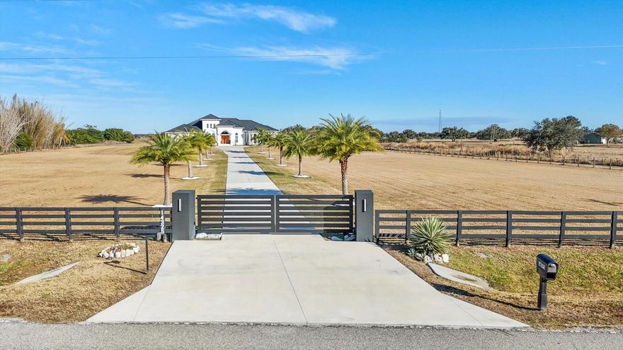 Welcome to one of the most extraordinary private estates in the area. Perfectly positioned on 6 fully fenced acres of pristine land. From the moment you enter through the automatic gate and travel the long palm lined driveway, you know you’ve arrived somewhere truly special. This spectacular residence features soaring ceilings and expansive open living spaces that create an immediate sense of grandeur. Every detail has been thoughtfully designed. From the extravagant landscaping with custom lighting and full irrigation system to the decorative rock accents that enhance drainage while elevating the property’s curb appeal. Inside, you’ll find one of the most impressive floor plans available. Multiple wet bar stations, private corridors with direct pool access, and breathtaking country views elevate everyday living. The primary suite is a private retreat of its own, featuring oversized boutique style closets and a built in concrete safe room. The chef’s kitchen serves as the heart of the home, ideal for entertaining on a grand scale or enjoying quiet evenings in. In addition to the spacious bedrooms, two large flex rooms offer endless possibilities like an executive office, a golf simulator lounge, private theater room, fitness studio, or creative space. Step outside to a resort inspired pool with a fresh modern design, outdoor kitchen, covered lounging areas, surround sound throughout, and ambient evening lighting that creates an unforgettable atmosphere. Whether hosting game nights, relaxing with friends, or enjoying peaceful sunsets, this outdoor space delivers. The fully equipped barn makes this a true equestrian property. The land allows animals to roam freely and comfortably, a rare lifestyle opportunity. Surrounded by growth and future development, including Terranova Equestrian Center just across the way and golf courses minutes away, this estate stands unmatched in quality, scale, and location. This is more than a home  it’s a private compound with long term upside and limitless potential.