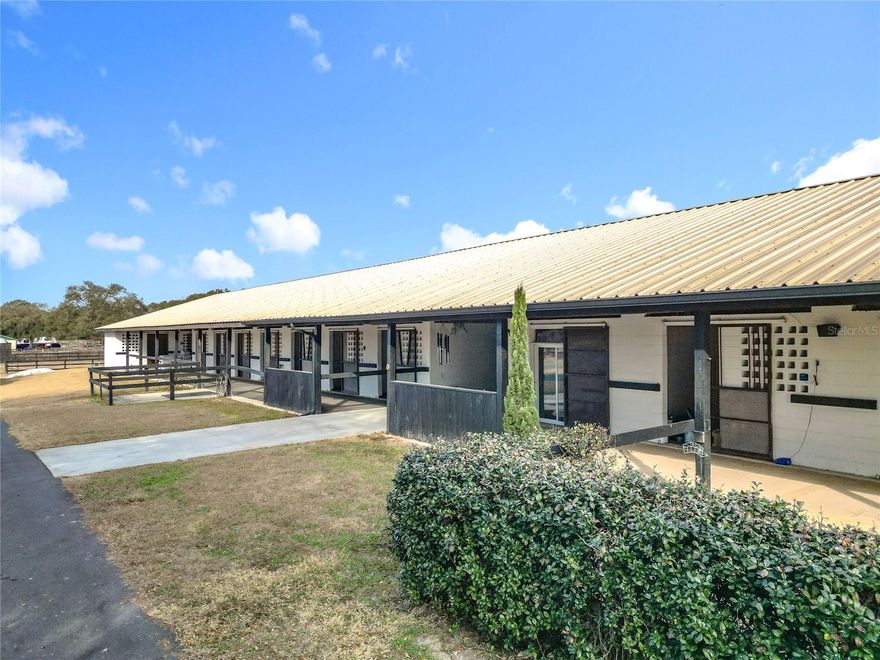 Set on 10 acres in the heart of Central Florida’s renowned horse country, this turnkey show farm offers an inviting balance of equestrian elegance and purposeful design. Located within the vibrant Starting Point Complex—home to established hunter, jumper, dressage, racehorse, and pleasure riding programs—the property is well-suited to a wide range of equestrian disciplines. Fully fenced, gated, and recently renovated, the farm makes a memorable first impression with a picturesque oak-lined drive that leads to the main improvements. The centerpiece of the property is a custom-designed 40-stall concrete block barn, thoughtfully arranged into three distinct wings to maximize comfort, efficiency, and flexibility. The West Wing features 18 stalls, a combined lounge and tack room, and two wash racks with running water. The East Wing includes 12 stalls, a spacious air-conditioned lounge, three newly constructed bedrooms, a full bathroom, and a separate laundry room. Each of these spaces is equipped with newer AC and heat units and can easily be adapted for use as offices, additional lounges, or expanded tack storage. The North Wing offers a beautifully renovated one-bedroom, one-bath apartment with updated plumbing and electrical, central AC and heat, new flooring, updated windows, and additional modern improvements. In total, the farm provides approximately 1,400 square feet of living space across five bedrooms and two bathrooms, offering exceptional versatility for staff, guests, or on-site living. Equestrian amenities include four paddocks with water lines already in place, three round pens, an expansive grass jump field, and classic three-board fencing. RV hookups add convenience for guests, and existing infrastructure allows for the easy expansion of additional paddocks if desired. Residents of Starting Point Complex also enjoy access to extensive bridle paths throughout the community, along with optional use of the community’s 5/8-mile training track. Conveniently located just four miles from HITS and approximately 18 miles from the World Equestrian Center, this property presents an excellent opportunity for those seeking a well-appointed farm with access to year-round training, competition, and spectating.