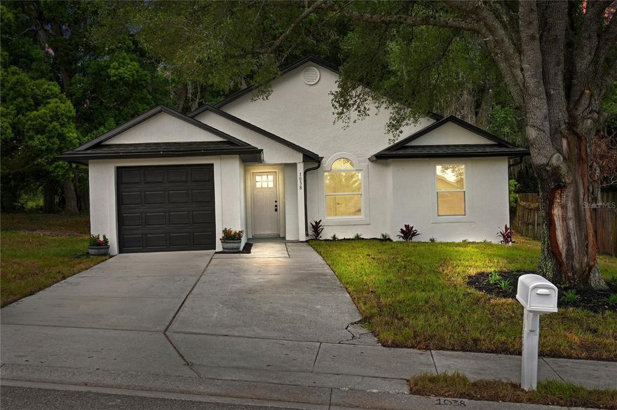 Fully renovated and move-in ready — 1038 Sheeler Hills Dr is a turn-key 4-bedroom, 2-bath home in the heart of Apopka, just north of Orlando. Every system, surface, and finish has been redone, so there's nothing left for a buyer to do but unpack. Step inside to a bright, open-concept great room with vaulted ceilings, oversized windows, and brand-new light-wood plank flooring that flows seamlessly through living, dining, and kitchen spaces.
The designer kitchen is the heart of the home — tall light-wood shaker cabinets with crown molding, polished quartz countertops, a hexagonal marble-look mosaic backsplash, and a full stainless steel appliance package (side-by-side refrigerator, electric range, microwave hood, dishwasher) anchored by a deep single-basin sink with matte-black gooseneck faucet. A sun-filled dining area opens directly to the backyard through new sliding glass doors. Both bathrooms have been taken to the studs and rebuilt: floating wood vanities with quartz tops, oversized framed mirrors with linear LED vanity bars, modern faucets and fixtures, and a spa-style walk-in shower wrapped in large-format porcelain tile with a built-in niche.
Bedrooms are generous, light, and finished to the same high standard — vaulted ceilings, new windows, fresh paint, and the same plank flooring (no carpet anywhere in the home). The exterior was not skipped: new windows throughout, new sod, fresh paint, and a new garage door with new opener motor. Located in a quiet, established Apopka neighborhood with quick access to SR-414, SR-429, and downtown Orlando — and minutes from Wekiva Springs State Park, Kelly Park, and the West Orange Trail. Pull together the renovation, the layout, and the location, and this is one of the cleanest move-in-ready offerings in 32703.