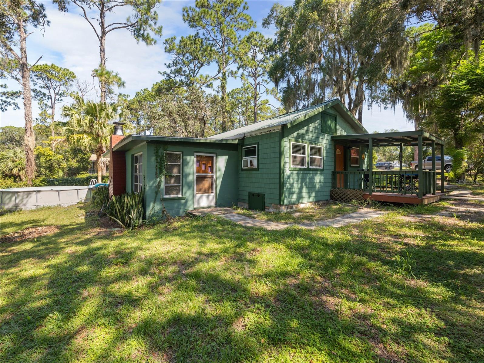 Escape to peace and privacy on this charming corner-lot retreat nestled along the serene shores of Wash Pond Lake. This 2 bedroom, 1 bath home offers everything you need for weekend getaways or full time living surrounded by nature. There is also an office/flex space right off of the master bedroom, offering extra space for whatever you may need. This home has been well cared for and you can feel the love as you enter the home. Enjoy tranquil mornings from your own boathouse and dock, perfect for kayaking, canoeing, or simply soaking in the beauty of the water right outside your front door. A metal roof was installed 10 years ago, new well pump (deep well) and updated electrical in 2011 provides peace of mind, while laminate flooring and carpet throughout make the home cozy and low maintenance. Curl up next to the cozy fireplace in the family room on those chilly Florida nights.
Step outside to a fully chain linked fenced yard, with plenty of room for a large shed or garage....all while sitting within the heart of the Ocala National Forest-a true outdoor lover's paradise. Whether you're casting a line, paddling around the lake, or enjoying the abundant wildlife, this property is made for those who crave simplicity and natural beauty. Only an hour away from Daytona Beach, this is an ideal spot for day beach trips or Daytona Bike Week! The Ocala National Forest provides lots of space to ride and enjoy the outdoors. This home is one you have to see to truly appreciate-schedule your showing today and see for yourself.