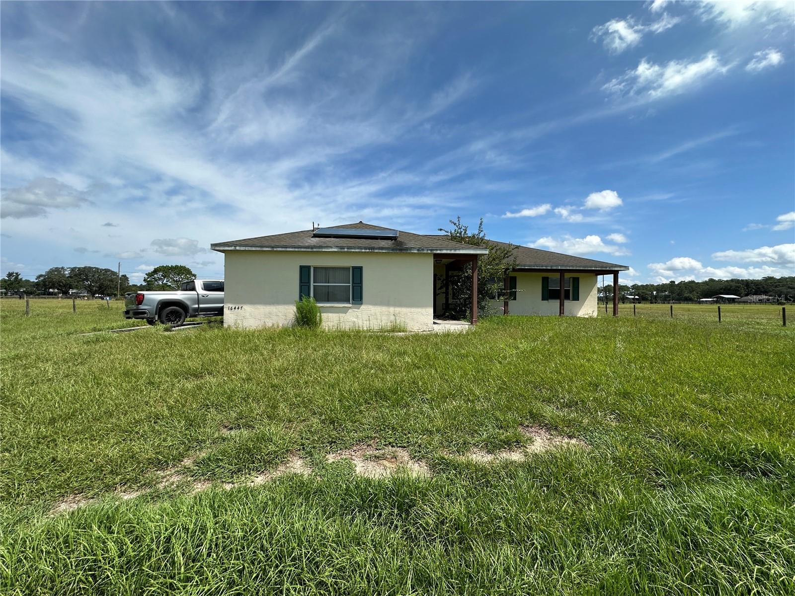 Peaceful country living meets modern convenience on this fully fenced 10.5-acre equestrian estate with no HOA. This 3-bedroom, 2-bathroom home offers open living space, featuring a split floor plan with the primary suite on one side and two bedrooms with a shared bath on the other. The spacious kitchen and family room combo is perfect for gatherings, while the inviting front porch is the ideal spot to relax and take in panoramic views of your green pastures. Designed with horse lovers in mind, the property includes three large grass pastures, a 36x36 center-aisle barn with five stalls, tack room, fly spray system, two hot/cold wash racks, and its own electric meter. A separate feed/storage shed, concrete walkway, and metal roof with insulation add to the thoughtful setup. High-speed fiber optic internet is already connected—rare for acreage properties! Additional features include a solar water heater, RV hook-up with second septic drain field, generator connection, and a 2-car garage. Move-in ready for both you and your horses, with electric fence wiring ready to activate. Built in 2001 and well-maintained, the home could benefit from some updates (reflected in the price) but is in great overall condition. The land is high, dry, and level—perfect for riding, gardening, or future additions. Just minutes from the Suncoast Parkway, enjoy an easy commute to Tampa while coming home to your private mini-ranch.