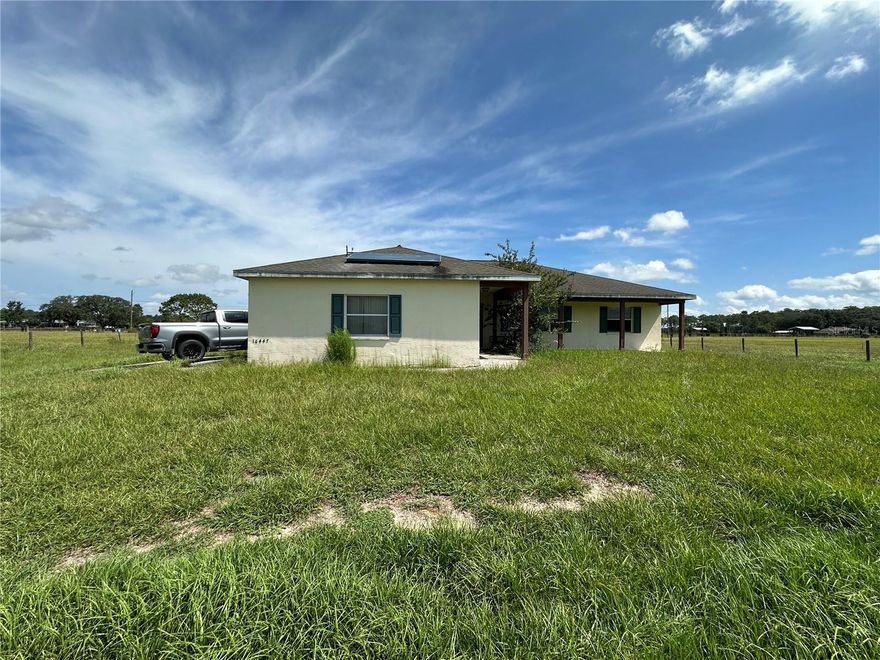Peaceful country living meets modern convenience on this fully fenced 10.5-acre equestrian estate with no HOA. This 3-bedroom, 2-bathroom home offers open living space, featuring a split floor plan with the primary suite on one side and two bedrooms with a shared bath on the other. The spacious kitchen and family room combo is perfect for gatherings, while the inviting front porch is the ideal spot to relax and take in panoramic views of your green pastures. Designed with horse lovers in mind, the property includes three large grass pastures, a 36x36 center-aisle barn with five stalls, tack room, fly spray system, two hot/cold wash racks, and its own electric meter. A separate feed/storage shed, concrete walkway, and metal roof with insulation add to the thoughtful setup. High-speed fiber optic internet is already connected—rare for acreage properties! Additional features include a solar water heater, RV hook-up with second septic drain field, generator connection, and a 2-car garage. Move-in ready for both you and your horses, with electric fence wiring ready to activate. Built in 2001 and well-maintained, the home could benefit from some updates (reflected in the price) but is in great overall condition. The land is high, dry, and level—perfect for riding, gardening, or future additions. Just minutes from the Suncoast Parkway, enjoy an easy commute to Tampa while coming home to your private mini-ranch.