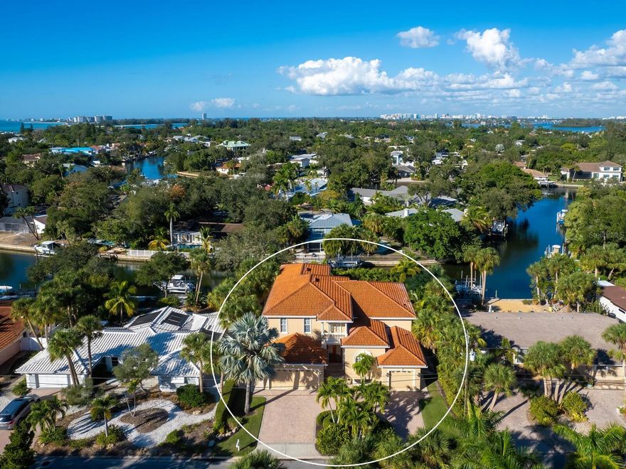 Reimagined, redefined, returned to market, reduced in price and ready for its new owner, this lovely home sits on a quiet canal just off the more heavily trafficked Grand Canal of Siesta Key, world renowned for its award-winning white sand beaches. Newer and elevated for storm protection, the residence is equipped with a whole house Generac home generator & home security system. The welcoming design of the property starts with its circular paver brick driveway leading you through the double door entry past the study/den or office into the Great Room with soaring ceilings & wet bar and contiguous to the primary suite as well as the dining room, eat in kitchen with breakfast bar & leading out to the screened porch with outdoor kitchen, overlooking the pool and double boat lift. A dramatic curved staircase leads up to the two guest bedrooms, loft/office, TV/media/family room and second level screened porch with serene views of the pool and canal. This home truly has it ALL!