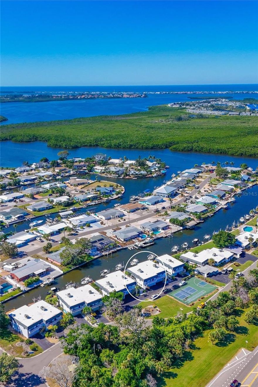 Location is paramount when it comes to Florida outdoor living. This exceptional waterfront two-story condominium, with 1,728 sq. ft. under air, 2 bedrooms, 3 baths, 2 bonus rooms, family, dining and living rooms, inside laundry closet and a 2-car oversized garage, features a dock in your backyard equipped with water, electricity and a 10,000-pound capacity boat lift. The property offers direct access to Palma Sola Bay, the Intercoastal Waterway, Egmont Key, and Gulf—all minutes away—with no fixed bridges impeding navigation. Surrounded by saltwater canals, the area provides excellent opportunities for kayaking and canoeing. Nature enthusiasts will appreciate the proximity to Neal Preserve and the sandy white beaches of Anna Maria Island (AMI), located just three miles from the property.
The residence emphasizes maintenance-free living, presenting numerous options to enjoy the surroundings both day and night. Manatees and dolphins are frequently observed in the saltwater canal directly in front of the screened-in porches, while the sunsets create a stunning backdrop. Upon entry, shiny bamboo flooring leads you down the hallway. The well-appointed chef’s kitchen includes stainless steel appliances, an induction stove and air fryer, solid wood cabinetry, under-cabinet lighting, and expansive granite countertops. The guest bedroom and updated guest bathroom are situated to the left, with the primary bedroom offering canal views. The living and dining rooms are located straight ahead, with easy access to the downstairs area via the adjacent staircase. Impact sliding doors lead out to screened-in porches on both levels. The first-floor features durable tile flooring, storage under the stair well, Endura flood waterproof drywall, a comfortable family room, a full bathroom, and two versatile bonus rooms currently utilized as guest bedrooms. Community amenities include an oversized heated pool, tennis/pickleball court, and a basketball court. In addition, shopping, restaurants, entertainment venues, downtown Bradenton, Sarasota, Longboat Key, St. Armands, UTC Mall, and Sarasota/Bradenton Airport are all conveniently nearby.  Don’t let this unique property get away. Schedule your private showing soon!