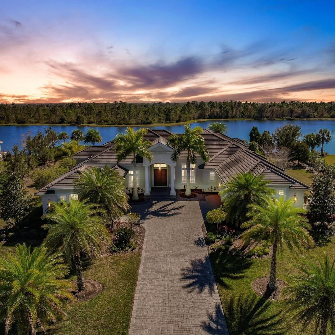 An exceptional estate with unmatched outdoor living. Experience luxury living in this custom-built Lakewood Ranch estate, gracefully situated on 1.19 acres of lush grounds in the exclusive gated community of The Concession. With over 5,000 square feet of thoughtfully designed living space, this home blends elegance, functionality, and serene natural beauty. OUTDOOR LIVING: Step outside and immerse yourself in the ultimate Florida lifestyle. The expansive lanai boasts a heated pool with an infinity spa, a tranquil water feature, and a travertine paver deck, creating an idyllic retreat. Entertain effortlessly in the fully equipped outdoor kitchen or unwind by the fire pit while taking in sweeping views of the serene lake and private preserve. This outdoor haven is perfect for relaxation and entertaining year-round. STORAGE AND PRIVACY: the home showcases a split floor plan with every bedroom featuring walk-in closets with custom built-ins and their own ensuite bathroom. The master suite is a private sanctuary featuring wood floors, a tray ceiling, and a warm sitting area. Dual dressing rooms offer ample storage, while the spa-inspired bathroom dazzles with marble countertops, an oversized walk-in shower, a freestanding tub, and tankless hot water. ELEGANT ENTERTAINING: The gourmet kitchen is a chef’s dream, adorned with stone countertops, a marble backsplash, top-tier appliances, and a walk-in pantry. Custom wood beams and zero-corner hurricane sliding doors in the family room create a seamless transition between indoor and outdoor living spaces. The formal dining and living areas are complemented by a built-out bar and a stunning wine closet with a wrought-iron gate, ideal for showcasing fine wines and spirits. A bonus room with a wet bar provides additional space for gatherings. SAFETY AND HURRICANE PROTECTION: This home is equipped with hurricane-impact windows throughout, a whole-house generator, a smart home equipment closet, and dual garages with space for four vehicles. These features, combined with the secure gated community setting, ensure peace of mind. EXCLUSIVE AMENITIES: The Concession spans over 1,200 acres with just 250 residences immersed in old Florida charm. It is home to the award-winning Concession Golf Club, featuring a Jack Nicklaus Signature Golf Course co-designed with Tony Jacklin. This world-class club has hosted elite tournaments, including the World Golf Championships and NCAA Championships. Minutes from the vibrant shopping, dining, and entertainment of UTC, Benderson Park, Main Street, and Waterside, this estate offers the perfect balance of tranquility and accessibility with none of the CDD fees.