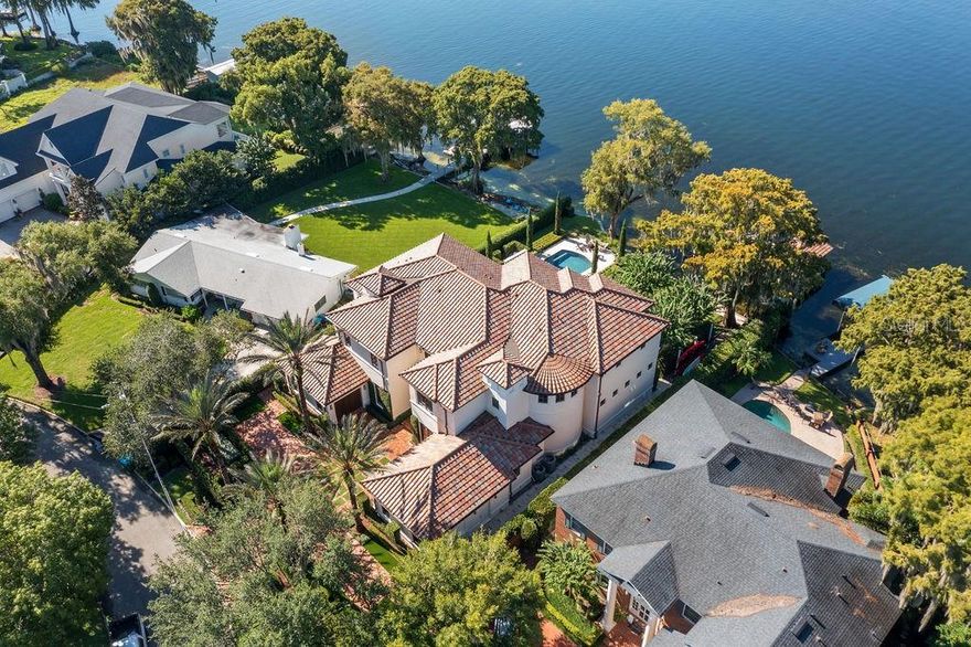 Truly magnificent estate on Lake Maitland — part of the Chain of Lakes with 100 feet of water frontage. Tastefully designed interior with over 6,400 square feet of living space, four bedrooms, five-and-a-half baths, a bonus room, a home office, a kitchen, and a wine cellar. Elegant formal living room with fireplace and formal dining room. Spacious gourmet kitchen comes with Sub-Zero appliances, gas range, granite countertops, access to the back patio, and water views. The formal dining area is just off the living room, which features a beautiful fireplace and built-in cabinetry. Beautiful travertine flooring, vaulted ceilings, crown molding, and custom built-ins. The most spectacular view of the lake was assigned to the primary suite upstairs. The home office or additional bedroom connects to the primary suite for added convenience for working or infant care. Three additional bedrooms with en-suites and plenty of closet space are upstairs. Private backyard, screened-in patio, gorgeous swimming pool, and a hot tub — all overlooking the lake. Meticulous landscaping where every inch is accounted for. Elegant details, natural stone flooring, 12-foot wood-beamed ceilings, and recessed lighting throughout. Three-car garage and a private gate for extra privacy. Home includes a covered boat dock with a lift. New roof, AC units, and copper gutters. Enjoy lake living on the Winter Park Chain of Lakes with amazing sunrise and sunset views.