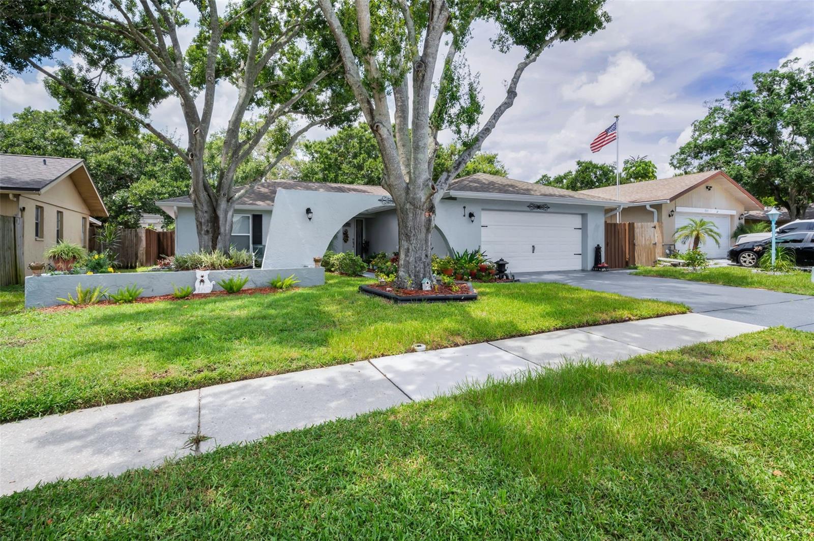 Welcome to this beautifully updated 3 bedroom, 2 bathroom home with an oversized 2-car garage in the heart of Palm Harbor! Located in a quiet community with NO HOA, NON flood zone, and zoned for top-rated Palm Harbor University High School, this home checks all the boxes. When you drive up you'll notice the curb appeal with lush landscaping and plants. Step inside to find brand-new laminate flooring flowing nicely all throughout the main living areas and kitchen, plush carpet in the bedrooms, and updated ceramic tile in both bathrooms. New modern light fixtures add a fresh touch. The spacious master suite offers an en suite bath with a double vanity with updated faucets and plenty of storage underneath. Two additional spacious bedrooms share a large second bathroom, also featuring a double vanity with updated faucets. The kitchen is perfect for everyday living with granite countertops, wood cabinetry, stainless steel appliances, and a breakfast bar. Sliding glass doors open to a large screened lanai with custom pull-down shades to keep the heat out on hot days, and a hot tub, ideal for relaxing or entertaining. Outside, enjoy a fully fenced backyard with beautiful lush landscaping, a pergola with cover for more space and entertaining, and plenty of privacy. The fence was stained giving it a unique look. Other updates include new plantation shutters in the primary bedroom and back bedroom. You can have all of this, plus being walking distance to shopping, dining, and entertainment. With its unbeatable location, updates, and desirable features - NO HOA, NON FLOOD ZONE, zoned for TOP RATED schools, this home is a must-see. Schedule your showing today!