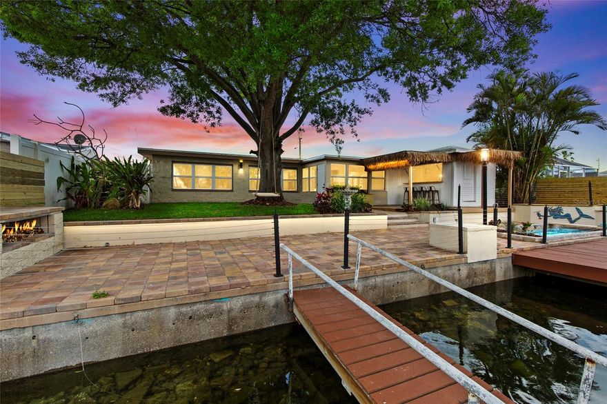 One or more photo(s) has been virtually staged. Welcome to your everyday waterfront getaway, where comfort, style, and outdoor living come together. This beautifully updated 4-bedroom, 2-bath canal-front home offers direct Gulf access and is perfectly suited for boating, entertaining, or simply enjoying the Florida lifestyle.
Recent updates include a brand-new roof, new AC system, updated electrical, and a fully refreshed interior, offering both peace of mind and modern appeal. Inside, the open-concept layout features wide-plank flooring, fresh finishes, abundant natural light, and a sleek electric fireplace that anchors the main living space. The fully updated kitchen is designed to impress with quartz countertops, stainless steel appliances, custom cabinetry, a built-in microwave, wine fridge, and a large peninsula with bar seating. A skylight fills the kitchen with natural light, while the Samsung Bespoke interchangeable panel refrigerator adds a modern touch. Wood-accent ceiling detail brings warmth and character to the space.
Just off the main living area, the Florida room provides additional flexible living space with beautiful backyard and canal views, ideal for relaxing, dining, or entertaining year-round. A spacious bonus living area with expansive windows further enhances the home’s bright, open feel and seamless connection to the outdoors.
The split-bedroom floor plan offers privacy, with generously sized bedrooms, updated ceiling fans, and ample closet space. Both bathrooms have been tastefully remodeled with modern vanities, upgraded lighting, and a beautifully tiled walk-in shower.
A separate laundry room adds convenience and functionality, featuring a new stackable Samsung washer and dryer.
Step outside to your private waterfront oasis. The backyard is designed for entertaining, highlighted by an impressive tiki bar experience featuring approximately 110 square feet of interior bar space, complemented by an additional covered outdoor seating area under a custom tiki hut with deck, accommodating 4 to 5 guests comfortably. Complete with seating, a refrigerator, wine glass hanging racks, rear shelving, and a fold-down serving window, this space creates a seamless indoor-outdoor entertaining environment.
Enjoy evenings by the outdoor fireplace, unwind beneath the mature shade tree with a swing, or cool off in the cocktail pool with custom tile detail.
The property also features sleek steel-wire railing for unobstructed canal views, a floating dock, and a 10,000-pound boat lift, making it easy to get out on the water at a moment’s notice. The expansive paved patio and multiple seating areas create the perfect setting for gatherings, while the fenced yard adds both style and function.
Out front, a circular driveway offers ample parking and welcoming curb appeal, framed by mature landscaping and a clean coastal aesthetic. Located just minutes from open Gulf waters, marinas, waterfront dining, and everyday conveniences, this home offers a rare opportunity to enjoy the true Florida waterfront lifestyle.