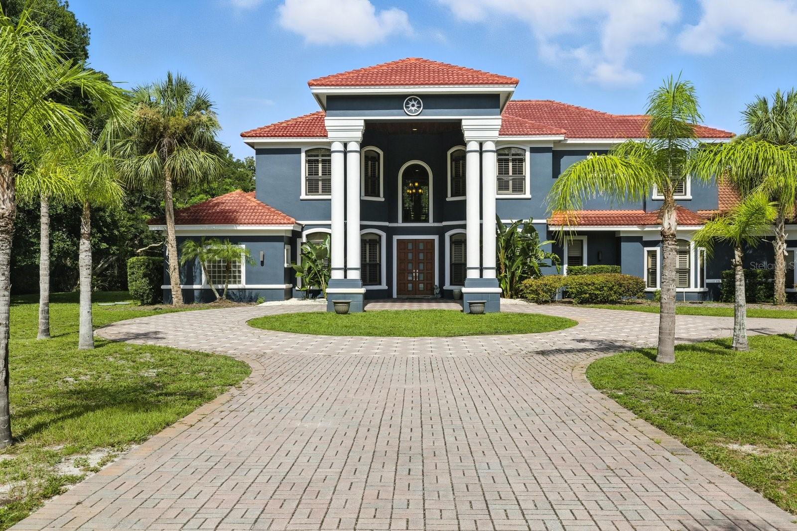 A Private Transitional Modern Estate Designed for Elevated Living.Privately gated and set on over 2.4 acres of manicured grounds, zoned R-A and located in unincorporated Pinellas County within an X flood zone, this custom-built transitional modern estate offers an exceptional opportunity to own a rare combination of architectural sophistication, privacy, and lifestyle-focused design. Completed in 2009 with enduring materials and thoughtful detail, the residence presents over 5,000 square feet of living space tailored for both grand entertaining and serene daily life. The zoning and acreage also provide equestrian and agricultural potential (Currently zoned for horses!), appealing to those seeking a more versatile luxury estate. An impressive 22-foot ceiling height welcomes you into the main living area, where an abundance of inviting natural light showcases sweeping views of the screen-enclosed, resort-style pool, private tennis and basketball court, and lush landscape beyond. The outdoor living area is equally impressive, featuring a covered summer kitchen with built-in grill, sink, and kegerator, perfectly suited for dining and year-round entertaining. The open interior layout is complemented by refined finishes with tile flooring throughout living spaces and custom architectural millwork. The gourmet kitchen anchors the home’s entertaining spaces with granite countertops, a center island, and breakfast bar seating—perfectly situated for effortless flow between indoor and outdoor gatherings. Downstairs, a custom-built bar creates a dedicated space for entertaining, while multiple balconies upstairs provide quiet vantage points to enjoy the property’s peaceful setting. The primary suite is a graciously proportioned private retreat, featuring a gas fireplace, dual walk-in closets, spa-style bath with dual vanities, and direct access to the pool terrace. Five additional bedrooms, a home theater, and a private executive office with custom built-ins provide versatility, while a large flex space upstairs offers a dedicated area for remote work, creative pursuits, or a secondary lounge.The home has been updated with three recently updated HVAC systems with four-zone climate control, includes an oversized three-car garage, GAS appliances, unmetered well water for irrigation and a long, gated drive that ensures complete privacy from the outside world. Every element of this residence speaks to the needs of today’s discerning buyer—those who value elegance, privacy, and the convenience of a self-contained lifestyle. Situated within and currently zoned for top-tier schools, this location Combines seclusion with accessibility, providing smooth connectivity for professionals on the move and executive amenities, this property offers a rare opportunity to acquire a legacy estate of architectural merit and enduring comfort. Call today to schedule your private viewing!