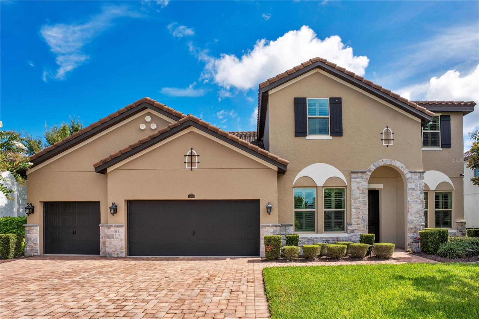 Imagine a home where lakefront serenity merges seamlessly with modern design and the energy of Central Florida’s most celebrated destinations. At 16653 Broadwater Avenue in Winter Garden’s Twinwaters community, that’s exactly what you get. Set on a 0.33-acre lot overlooking the 2,500-acre Johns Lake, this 4,046-square-foot residence features four bedrooms, five full bathrooms, and a layout d for both flexibility and flow. Public records list five bedrooms; a versatile flex room with a closet is currently styled as an office but can easily transition into a fifth. The main level anchors daily life with a primary suite featuring custom walk-in closets, a gourmet kitchen outfitted with premium finishes and top-of-the-line appliances, and a family room designed to connect effortlessly with the outdoors. Walls of folding glass doors reveal a screened patio and summer kitchen, perfect for entertaining or quiet reflection, with sweeping views that catch both sunrise and sunset. A dedicated movie room, separate dining room, and upstairs accommodations balance private comfort with social space. Recent enhancements include luxury vinyl plank flooring, custom-built closet systems in every bedroom, new carpet, and a fresh interior palette, all completed in 2024. Energy efficiency is elevated by owned solar panels, installed in 2016, adding sustainability to style. Step outside and the lake lifestyle takes center stage. A private dock with an electric boat lift and two drive-on jet ski slips makes boating, fishing, and watersports part of daily living. The stone-accented façade and manicured surroundings enhance the home’s modern character, while Twinwaters amenities — a pool, playground, and trails — enrich the neighborhood experience. Beyond the community, the location places you minutes from Hamlin Town Center and Winter Garden Village for shopping and dining, and the historic streets of Downtown Winter Garden with its boutique shops and Saturday Farmers Market. Walt Disney World Resort and Orlando’s attractions are also within easy reach. This is not just a residence; it is a lifestyle defined by water, light, and modern design in one of Winter Garden’s most desirable settings.