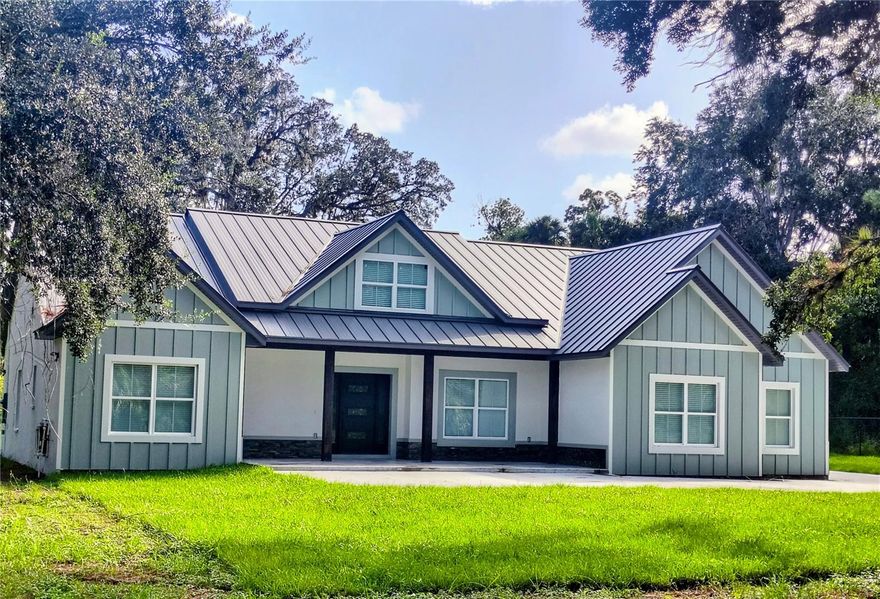 Welcome to your new EXCLUSIVE home!!  No HOA and no CDD.  Located on almost 1 acre of land on a dead road, with room to add other workshop or garage or a pool! This stunning home has a sleek metal roof and premium updates inside.  When you enter the foyer you have a panoramic view of the great room, dining area, and the beautiful kitchen with a stone countertop island ready for entertaining. THE ELECTRIC RANGE IS A ALSO A CONVECTION OVEN AND AIR FRYER. The high ceilings give a very open feeling when you walk in. The xtra large ceiling fan in the great room keeps the air moving. The patio doors are ready for triple opening to allow access to the outdoor kitchen area or just to sit with your coffee and enjoy the expansive yard view! The back bedroom allows access for visiters to have access to the patio for their relaxation and coffee The backyard has enough trees to give areas of shade for reading and quiet time. The 1/2 bath in the garage keeps from tracking in dirt to the house. There is also a large sink hooked up in the garage to allow cleaning up after yard work.