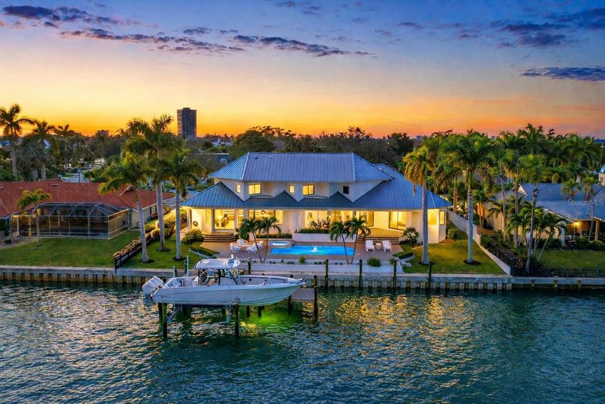 Perfectly positioned on coveted Robin Drive at the front of Bird Key, this fully reimagined bayfront residence captures Sarasota living at its finest. Originally built in 1996 and completely remodeled with exceptional attention to detail, the home blends timeless elegance with clean, modern lines and elevated materials selected for beauty and performance. Panoramic vistas span Sarasota Bay, the downtown skyline, and the iconic Ringling Bridge, presenting a stunning scene from sunrise through sunset. As evening falls, city lights shimmer and the Ringling Bridge illuminates, casting a soft sparkle across the Bay—a timeless view that never loses its allure. Set on protected waters ideal for boating, the property offers 120 feet of deep-water frontage at the junction of Bird Key’s Pompano Pass waterway, with unobstructed access to Sarasota Bay, Big Pass, and the Gulf —an exceptional opportunity for boating enthusiasts.
Inside, more than 4,000 square feet of thoughtfully designed living space unfolds across two light-filled levels. Soaring ceilings up to 14 feet and expansive walls of glass frame stunning bay views throughout. The front sitting room features a statement fireplace wall and flows seamlessly into the dining area, gourmet kitchen, and family living space—perfect for entertaining and everyday living.
The chef’s kitchen offers custom cabinetry, generous storage, a well-proportioned center island, and a discreet back kitchen and pantry with additional sink, appliances, and prep space. Premium Sub-Zero, Wolf, Bosch, and Miele appliances are complemented by sleek pop-up outlets. A nearby powder bath provides convenient access to the pool.
Sliding glass doors open to an expansive pavered pool deck for seamless indoor-outdoor living. The primary suite, privately located on the main level, features direct pool access, dual walk-in closets, a dressing area, and a luxurious spa-inspired bath with dual vanities, a seated vanity, soaking tub, and designer lighting. A spacious office and second powder bath are also located nearby.
Upstairs are two en-suite bedrooms with bay views and a versatile bonus room ideal for guests or media use. Outdoors, enjoy a private waterfront oasis with a sun-drenched deck, pool, heated spa, and stone steps leading to the bay. The newly constructed seawall and Trex dock include fish and dock lights, a 24,000-pound boat lift, and kayak and jet ski lifts.
Additional features include a circular driveway, three-car garage with Tesla charger, new metal roof, and irrigation well. Located in prestigious Bird Key, residents enjoy proximity to downtown Sarasota and St. Armands Circle, with optional membership at the Bird Key Yacht Club and nearby Bird Key Park.
This is a rare offering of refined waterfront luxury in one of Sarasota’s most sought-after bayfront locations.