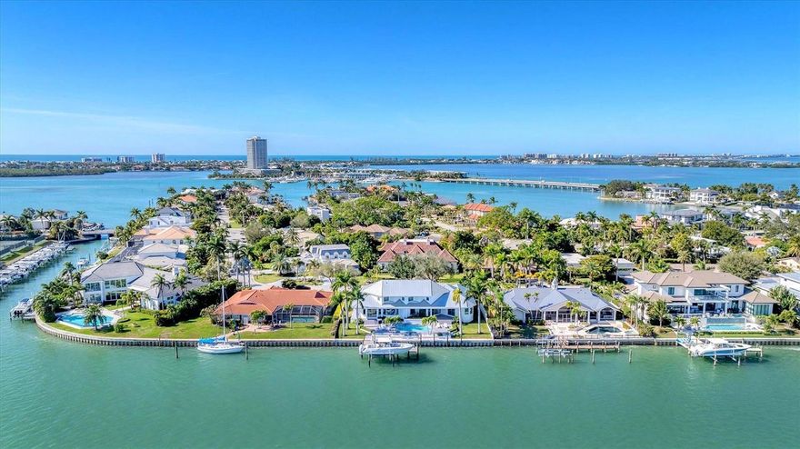 An exceptional opportunity on coveted Robin Drive in Bird Key, this fully reimagined bayfront home captures Sarasota’s waterfront lifestyle at its finest. Recently transformed through a meticulous, top-tier renovation, the residence showcases impeccable craftsmanship, elevated finishes, and a seamless blend of sophistication and comfort—where every detail and major system has been thoughtfully curated for effortless, modern coastal living. Elevated above the floodplain with a ground level over 10 feet, sweeping panoramic views span Sarasota Bay, the downtown skyline, and the iconic Ringling Bridge—creating a breathtaking backdrop from sunrise to sunset, with city lights shimmering across the water in the evening. Inside, more than 4,000 square feet of light-filled living space unfolds across two thoughtfully designed levels. Soaring ceilings up to 14 feet and expansive walls of glass bathe the interiors with natural light while framing unobstructed bay views throughout. The main living areas flow seamlessly from the inviting sitting room with a statement fireplace to the dining area and custom-designed kitchen, opening to the family room with a built-in bar—a wonderful gathering area to enjoy the gorgeous backdrop of the bay and downtown lights. The kitchen is anchored by a striking waterfall island and features designer-appointed custom cabinetry, premium Sub-Zero, Wolf, Bosch, and Miele appliances, and refined integrated details throughout. A fully equipped back kitchen and pantry, complete with an additional sink, appliances, and generous prep space, enhances functionality while maintaining a clean, polished aesthetic. The primary suite, privately positioned on the main level, offers direct access to the pool, dual walk-in closets, and a spa-inspired bath with a soaking tub, dual vanities, and elegant finishes. A dedicated office and two powder baths complete the main level. Upstairs, two en-suite bedrooms with bay views, a versatile bonus room, and an additional office space provide comfortable accommodations for family and guests. Outdoor living is equally compelling, featuring an expansive paver terrace, heated pool and spa, and unobstructed views of Sarasota Bay, downtown, and the Ringling Bridge—creating a serene waterfront retreat designed for everyday enjoyment. Set on protected waters, the property offers 120 feet of deep-water frontage along Bird Key’s Pompano Pass, with direct access to Sarasota Bay, Big Pass, and the Gulf. A newly constructed seawall and Trex dock feature fish and dock lighting, a 24,000-pound boat lift, and dedicated kayak and jet ski lifts—perfectly suited for an exceptional boating lifestyle. Additional highlights include a circular driveway, three-car garage with Tesla charger, and irrigation well. Bird Key offers an exceptional coastal lifestyle in one of Sarasota’s most coveted neighborhoods, just moments from downtown’s restaurants, shopping, and cultural venues, as well as the boutiques and dining of St. Armands Circle and the shoreline of Lido Beach. The Bird Key Yacht Club is currently undergoing a full redevelopment and is expected to reopen as a premier destination for boating, tennis, dining, and an active social scene.