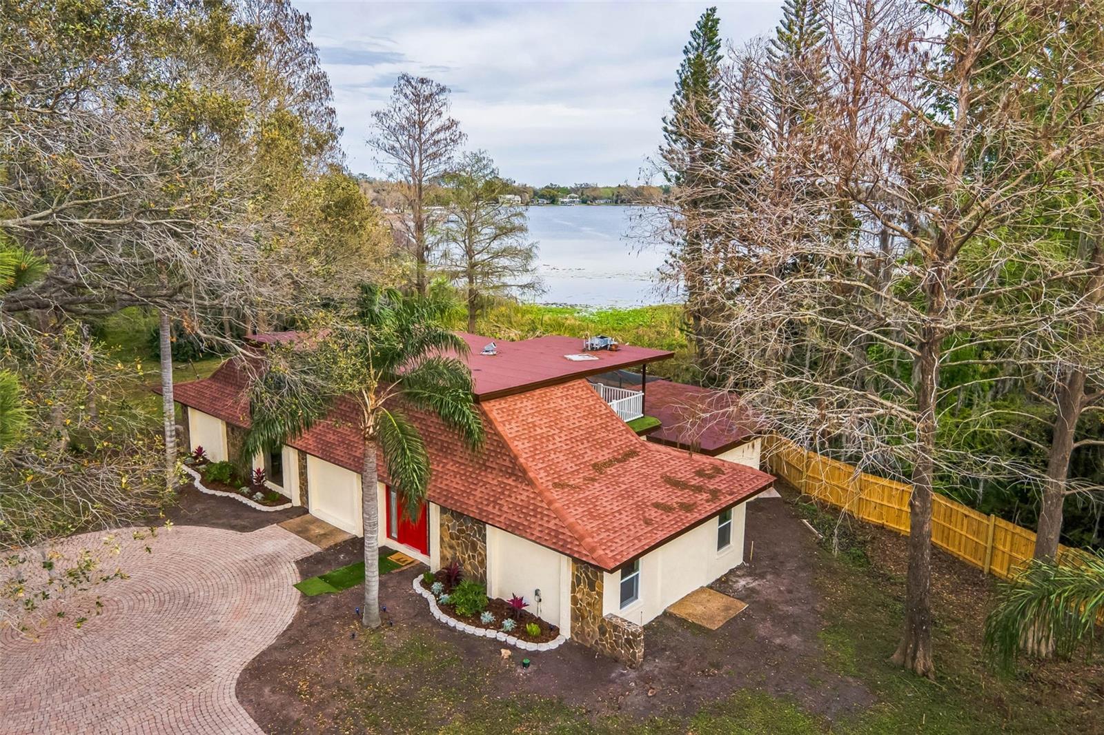 Your Private Escape on Lake Magdalene. Tucked away on a private half-acre lot, with no HOA, and nothing but peace, water, and sky—this is lakefront living at its purest. Fully remodeled with both comfort and adventure in mind, this 4-bedroom, 3 1/2-bathroom pool home invites you to slow down and soak up life on the water. Step inside to find crown molding and luxury vinyl plank flooring leading you into a foyer where a striking stone feature wall and modern light fixture set the tone. Double doors open to a versatile sitting room or office, complete with built-in shelving. The kitchen is a true showpiece—quartz countertops with barstool seating, stainless steel appliances with vent hood, and a farmhouse sink perfectly framed by pool and lake views. Natural light pours in from two walls of sliding glass doors in the living room with modern tile flooring throughout, creating a seamless indoor/outdoor experience. Just off the kitchen, the dining nook makes every meal feel like a retreat. The first-floor owner’s suite offers its own sitting room and sliding glass access to the lanai, plus double closets for generous storage. The ensuite bath features a spa-inspired shower with floor-to-ceiling tilework, a modern vanity, and LED lighting. Upstairs, a private balcony off one of the bedrooms with a ceiling fan offers panoramic views of both the pool and Lake Magdalene—perfect for morning coffee or sunset reflections. All the major updates are done for you—brand-new roof (2024), AC (2024), and water heater—so you can simply move in and start living lake life. And while it feels a world away, you’re just minutes from Tampa’s shopping, dining, and I-275. Busch Gardens and Adventure Island are nearby for weekend fun, while USF and Moffitt Cancer Center provide the convenience of close proximity for work, school, or healthcare. Opportunities like this are rare. Schedule your private showing today and claim your piece of paradise.