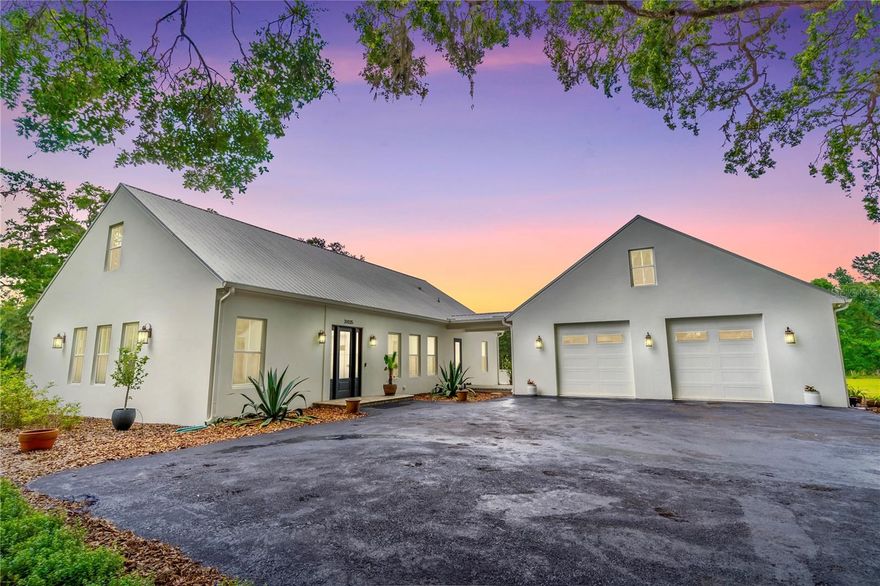 This exceptional custom estate at 31035 Pasco Rd. offers the perfect blend of quiet luxury, modern efficiency, and room to grow. Set on 3.35 private acres at the end of a picturesque 500-foot driveway lined with young white myrtles beneath majestic grandfather oaks, this property delivers both serenity and an impressive sense of arrival.

Thoughtfully designed and quality-built, the home features 4 bedrooms, 5 bathrooms, 6 car-garage and 2,976 square feet of beautifully maintained living space, including a flexible split floor plan with a private mother-in-law suite. The expansive great room flows seamlessly into the outdoor living area through towering sliding glass doors that fully open to a stunning covered porch—complete with a gas fireplace and TV—perfect for entertaining or enjoying breathtaking sunset views year-round.

At the heart of the home, the chef’s kitchen is anchored by an oversized quartz island and equipped with a 5-burner gas cooktop, built-in oven, and pot filler—ideal for both everyday living and hosting. The luxurious primary suite offers direct porch access and features dual vanities, generous his-and-her closets, a deep soaking tub with air jets, a walk-in shower, and a private water closet. Two additional bedrooms share a Jack-and-Jill bath, while a third full bath provides convenient access to the outdoor living space. Both the primary and third bathrooms are thoughtfully designed for wheelchair accessibility.

Car enthusiasts and hobbyists will appreciate the oversized 6-car garage with ample ceiling height for a car lift. Additional highlights include a large laundry room with sink and storage, climate-controlled attic space for excellent opportunity for a 5th bedroom, office, or bonus room and a tankless gas water heater ensuring endless hot water.

Ideally located just minutes from Interstate 75, everyday conveniences like Publix, local dining, and nearby parks are easily accessible—offering the perfect balance of peaceful country living and modern-day convenience.

This is a rare opportunity to own a one-of-a-kind estate that truly has it all—space, luxury, privacy, and functionality. Schedule your private showing today and experience it for yourself.