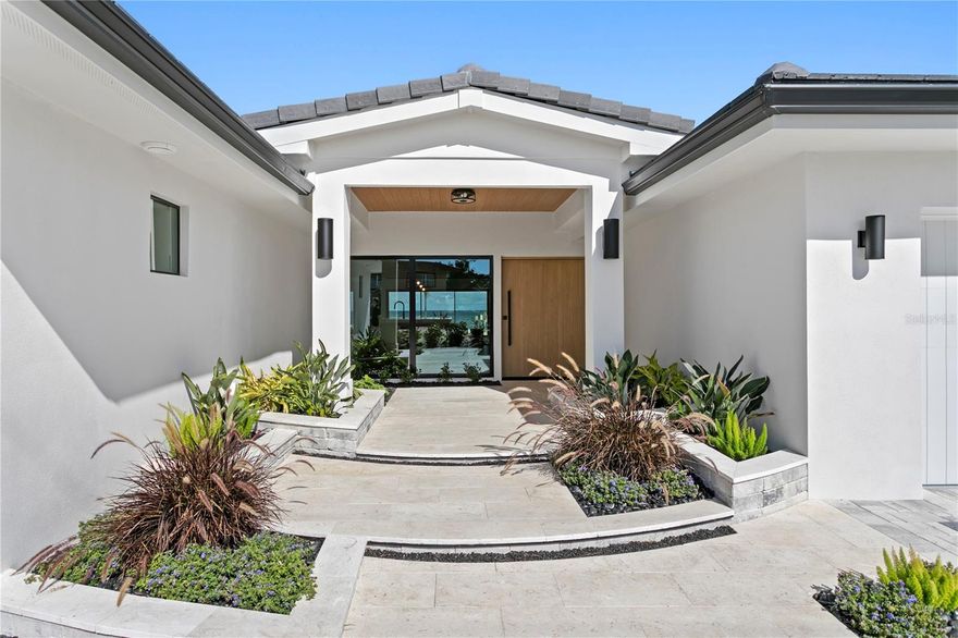 On the open water of Tampa Bay in a quaint neighborhood called Tropical Shores, this fully renovated custom waterfront residence offers refined coastal luxury just one mile from vibrant Downtown St. Petersburg and steps from the waterfront Lassing Park.  Completely transformed with no expense spared, the home showcases high-end designer finishes throughout, blending modern elegance with warm coastal sophistication. Expansive living spaces feature vaulted beamed ceilings, wide-plank flooring, custom millwork, and walls of glass that frame breathtaking open water views and fill the home with natural light. The kitchen is anchored by dramatic natural stone countertops and backsplash, custom cabinetry, premium appliances, and an oversized island designed for entertaining. Living and dining spaces flow seamlessly to the waterfront, creating an effortless indoor-outdoor lifestyle. Luxurious bathrooms feature statement marble, custom vanities, and spa-quality fixtures, while curated lighting and architectural details elevate every space. The backyard is truly the showpiece of this property with a gorgeous pool and expansive outdoor living space designed for both entertaining and relaxation.  Enjoy direct boating access to Tampa Bay with a 20,000-lb boat lift, new seawall, and beautifully designed outdoor living areas overlooking the water.  Completely updated and move-in ready, (could be sold furnished) the home experienced no flooding, offering peace of mind along with exceptional design and craftsmanship.  Tropical Shores offers a rare combination of privacy, open water and downtown St Pete views and a true waterfront lifestyle hard to match.