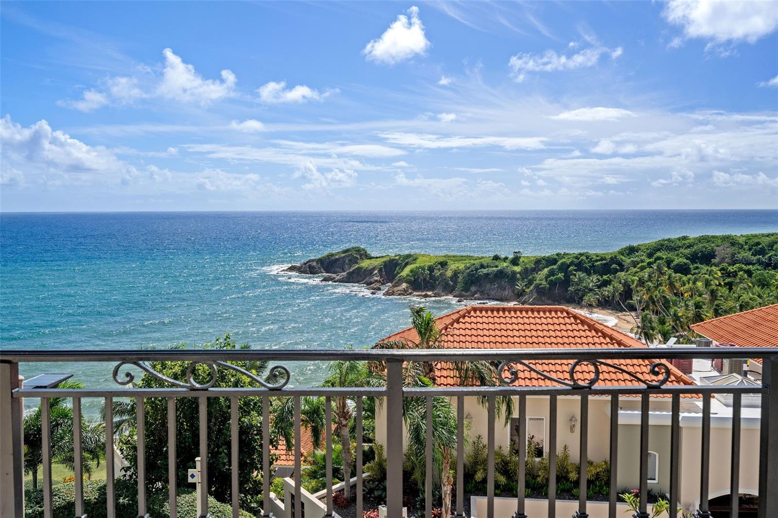 Perched atop a hill in the exclusive Shell Castle Club neighborhood of Palmas del Mar, this Spanish-style townhouse offers a lifestyle of elegance and tranquility with views that take your breath away. Imagine waking up each morning to the shimmering expanse of the ocean to the east and ending your day with sunsets over the lush rainforest and vibrant resort to the west. Spanning four levels, the home is crowned with a rooftop terrace featuring a pool, the perfect spot to unwind or entertain while soaking in the panoramic scenery. Step inside to an open-plan living area that flows effortlessly onto expansive covered terraces and balconies, where the gentle Caribbean breezes invite you to linger. With three spacious bedrooms, easily convertible to four, this home adapts to your needs, whether it’s creating a cozy guest room or a private office. The property also includes a convenient laundry room, a one-car garage, and a generator, ensuring comfort and convenience. While the home’s elevator is currently non-functional, its potential to connect the levels enhances its appeal.
Located in Palmas del Mar, a 2,700-acre master-planned resort community, this home offers more than just a residence—it’s a lifestyle. Palmas del Mar is known for its world-class amenities, including two championship golf courses, a state-of-the-art tennis center, a marina, and a vibrant equestrian center. Dining options abound with a variety of restaurants, and outdoor enthusiasts will enjoy miles of walking and biking trails. For families, Palmas Academy, a highly regarded bilingual school, provides excellent educational opportunities within the community.
This timeless Mediterranean gem offers the perfect blend of old-world charm and modern practicality, creating an idyllic retreat for those seeking a serene yet vibrant lifestyle in the heart of Palmas del Mar.